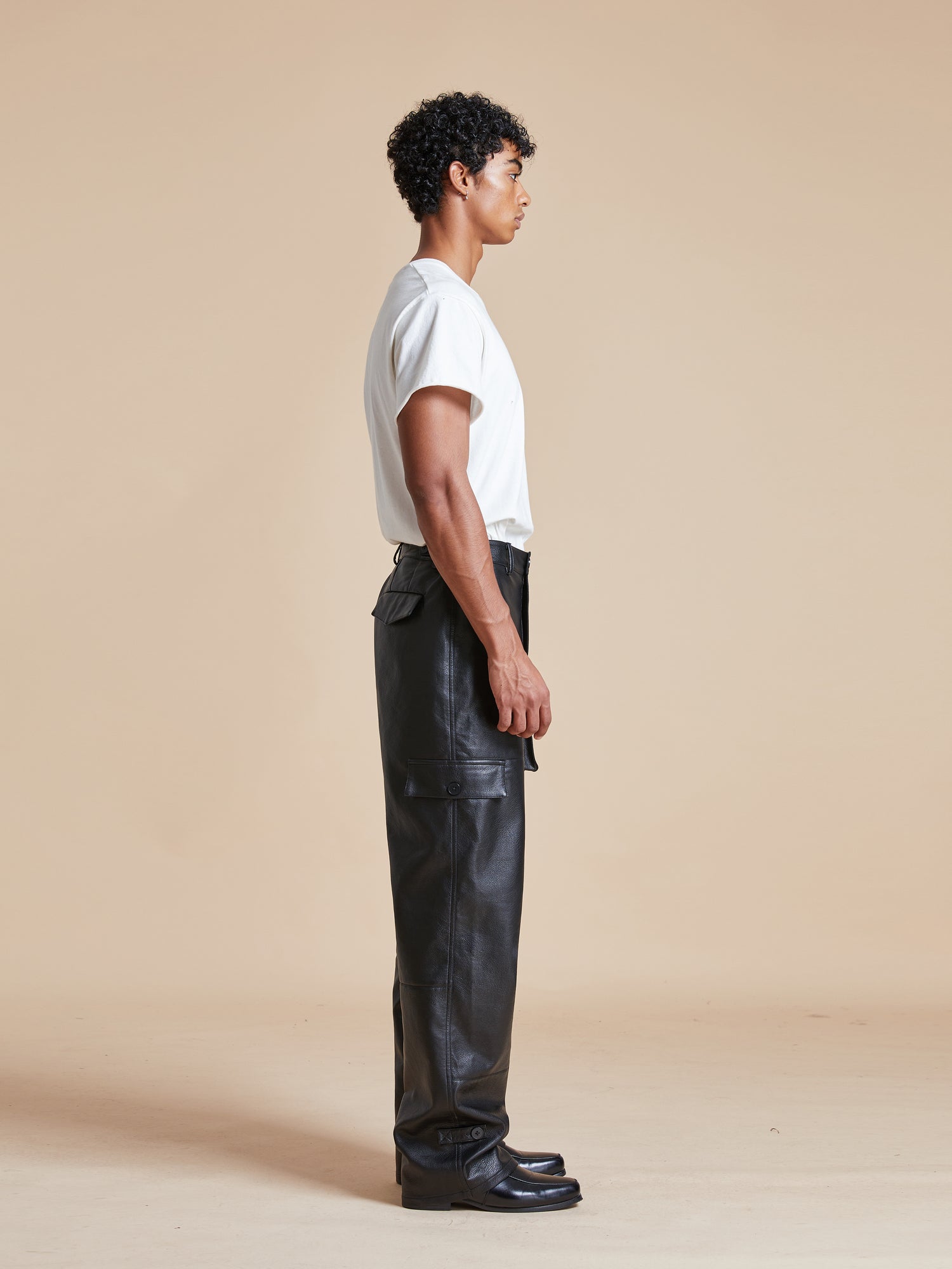 A man wearing Found Faux Leather Cargo Pants and a white t - shirt.