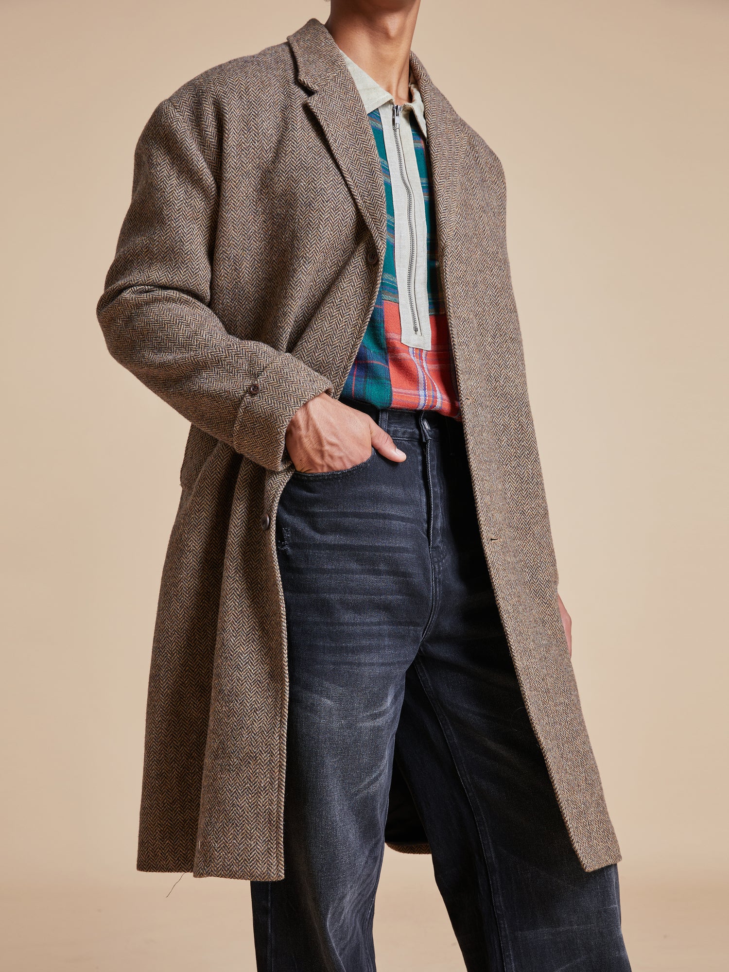A man wearing a Found Elm Tweed Long Top Coat and jeans.