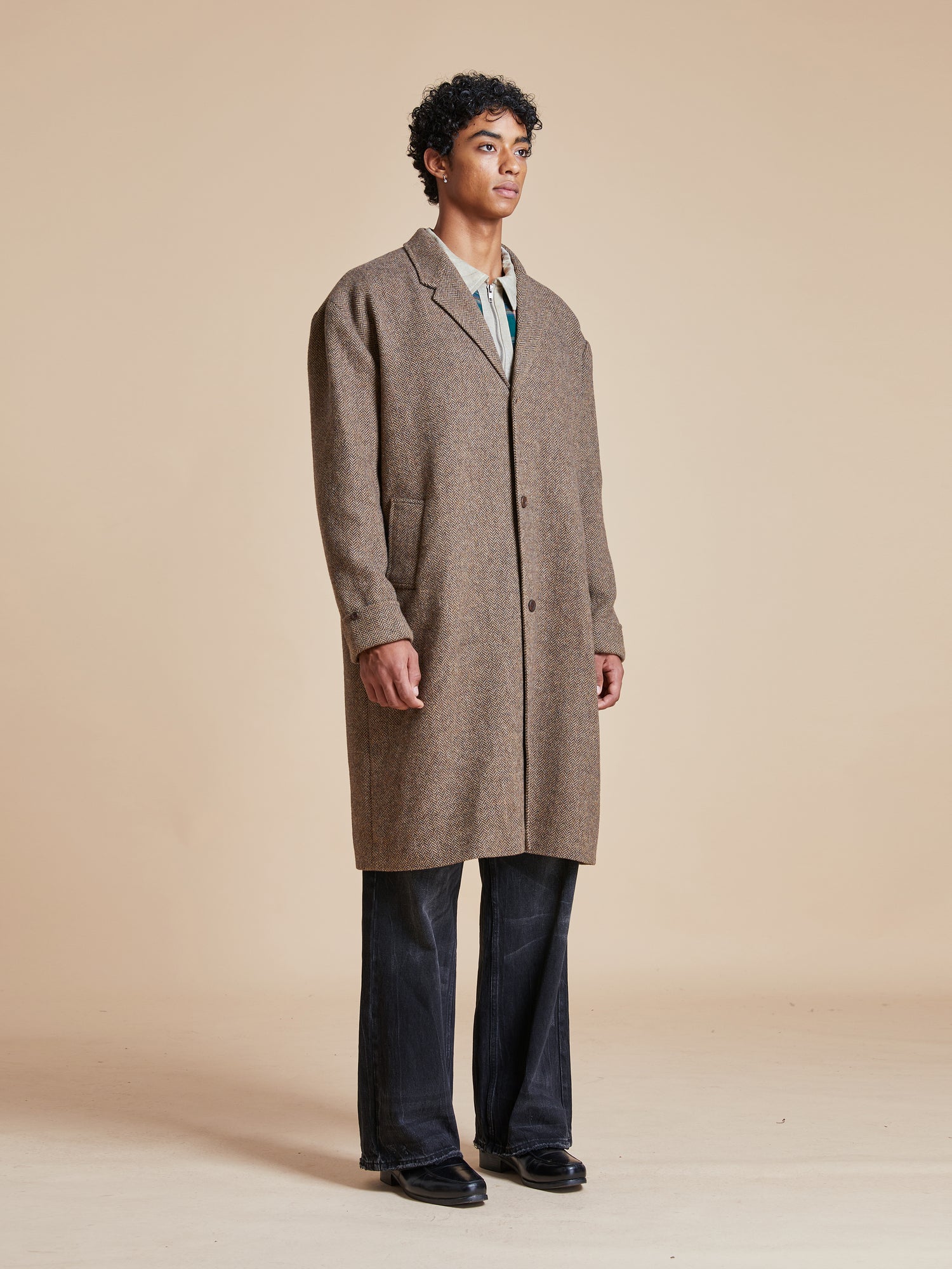 A man is standing in an Elm Tweed Long Top Coat by Found.