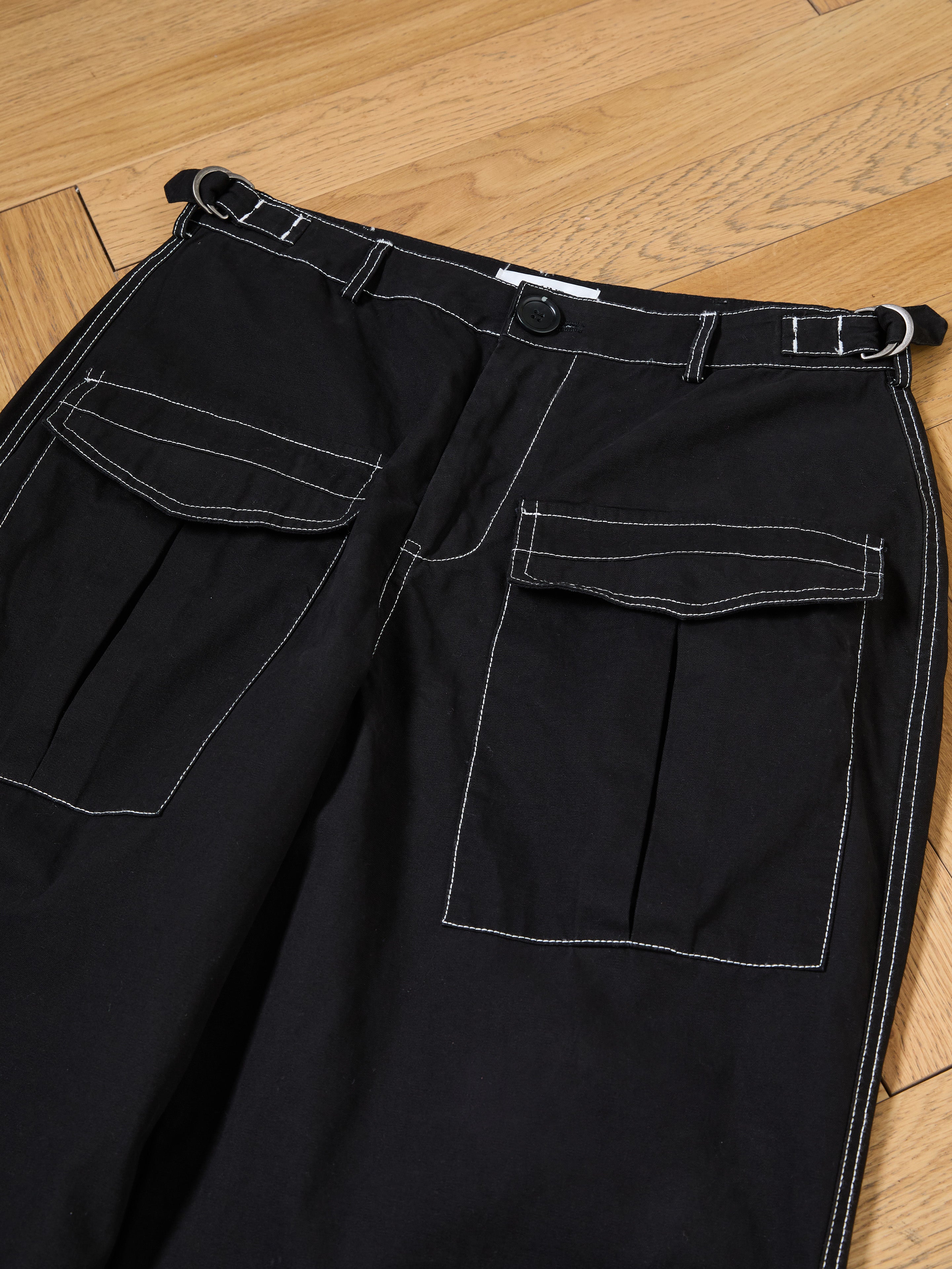 Lucca Black Contrast Pocket Pants by FOUND feature white stitching and large front pockets in a relaxed straight-leg fit, laid on a wooden floor.