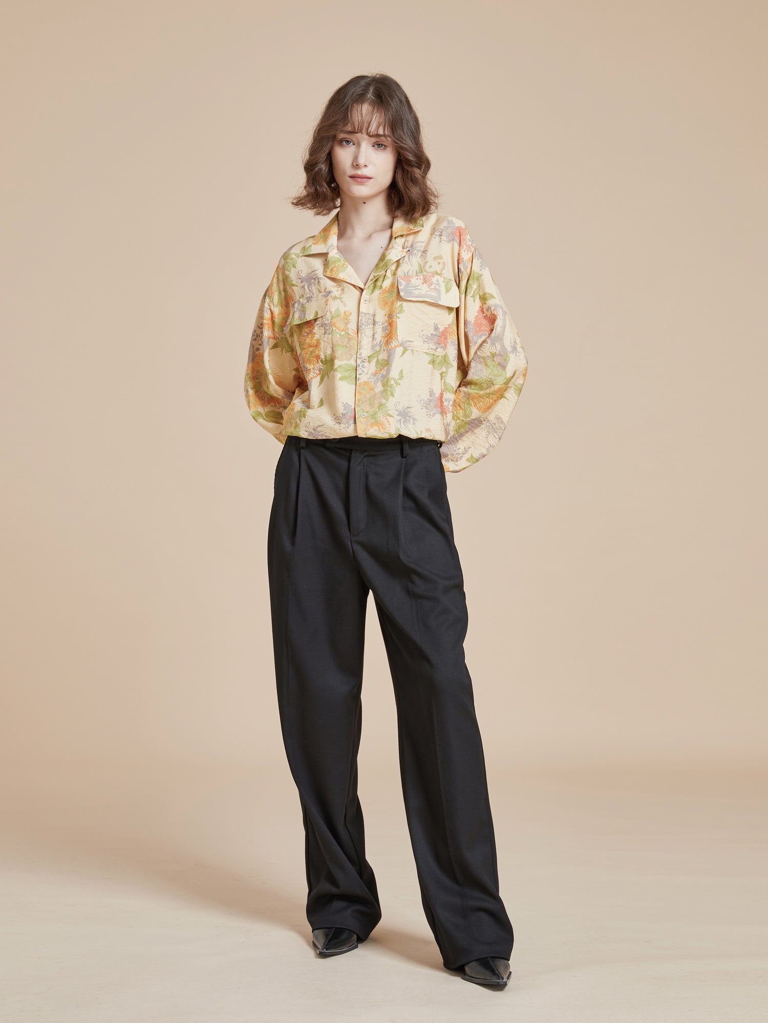 A model wearing a yellow shirt featuring Meraj Vase Pot motifs and black wide leg pants. (Brand name: Found)