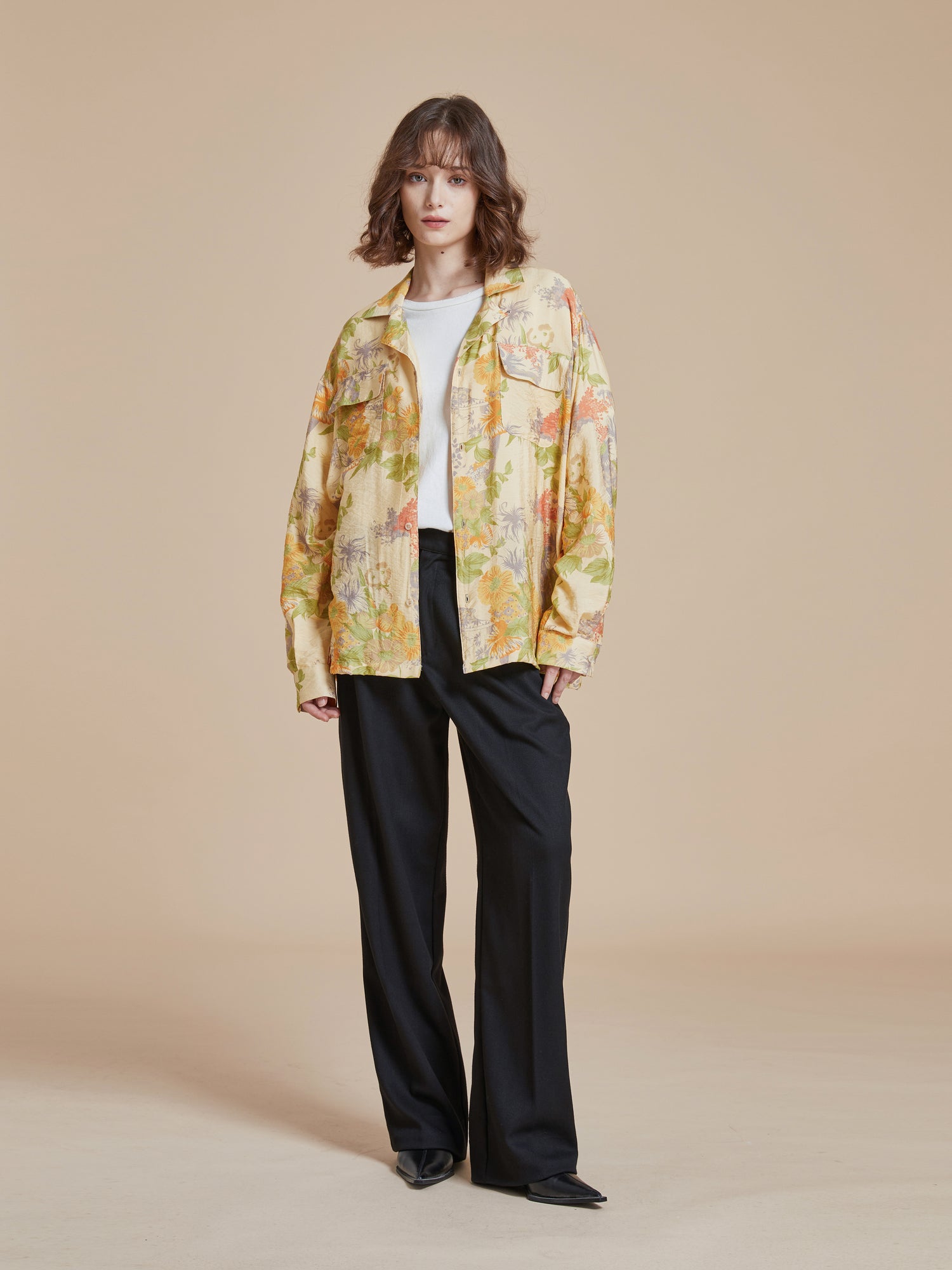 A model wearing a yellow floral jacket with nature-inspired Phulkari motifs and black trousers from Found's Meraj Vase Pot Long Sleeve Camp Shirt.