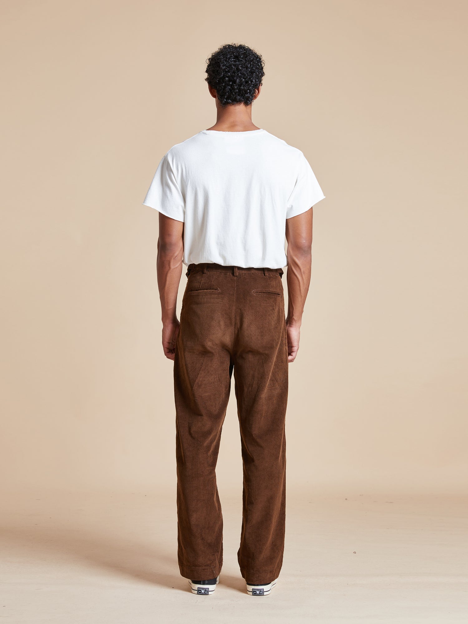 The back view of a man wearing Found Multi-Plaid Patch Corduroy Pants with fabric patches.
