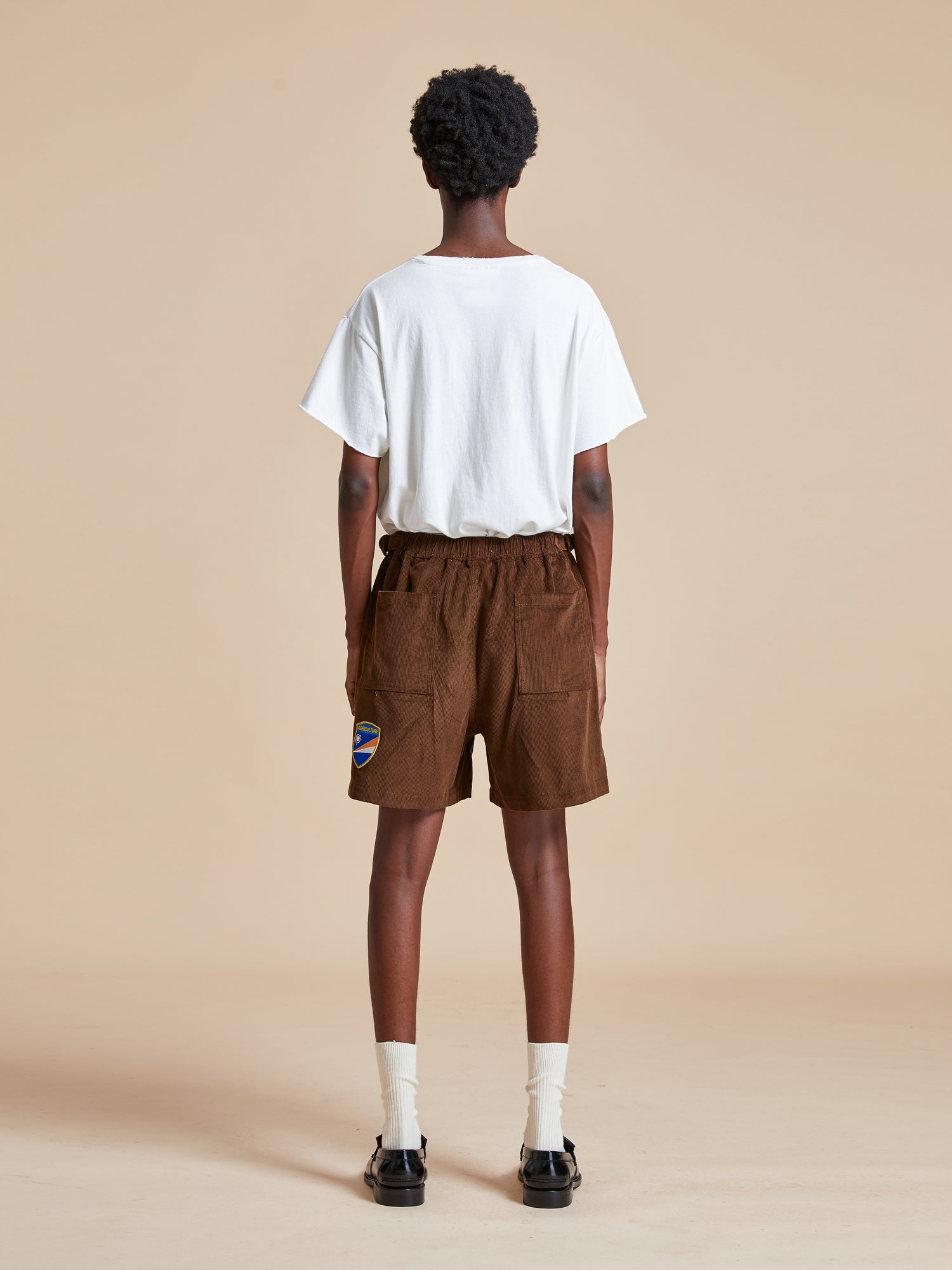 The back view of a man wearing Found Canoe Multi Patch Corduroy Shorts.