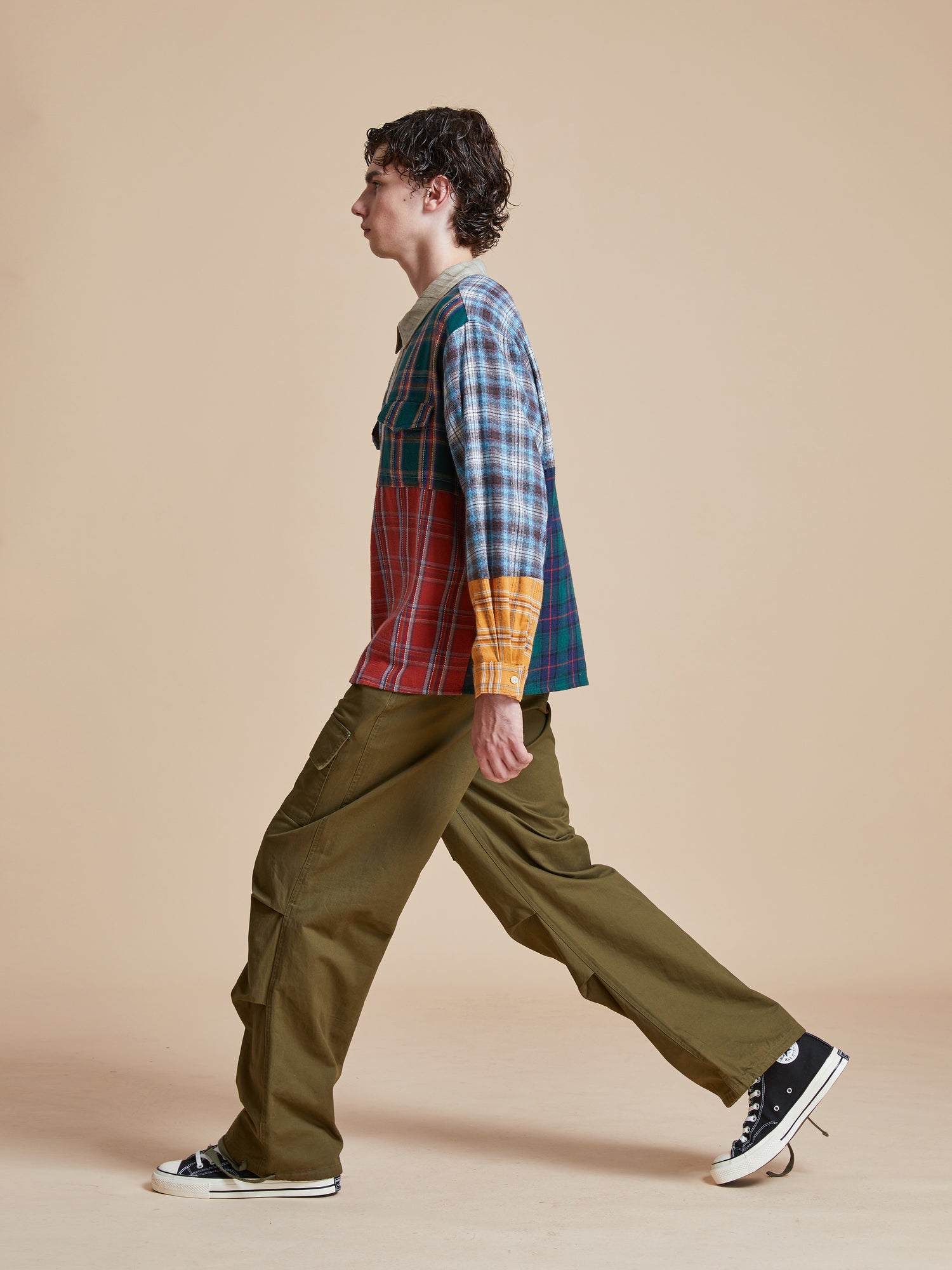 A man is walking in a Multi Plaid Tartan Shirt by Found and sneakers.