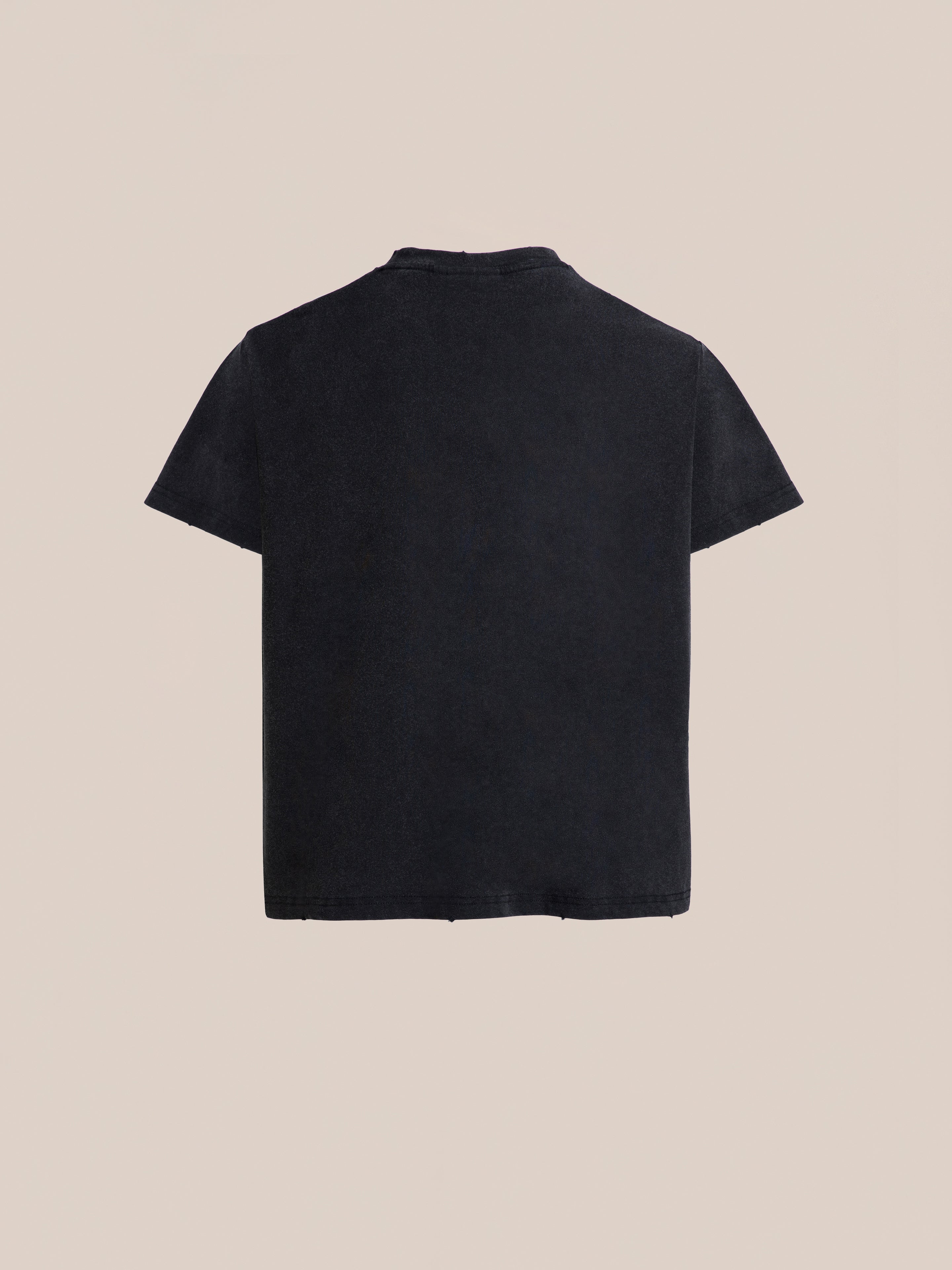 An Ornament Pocket Tee from FOUND, showcased in plain black with short sleeves, is displayed against a light beige background. The image features the back view of the t-shirt.