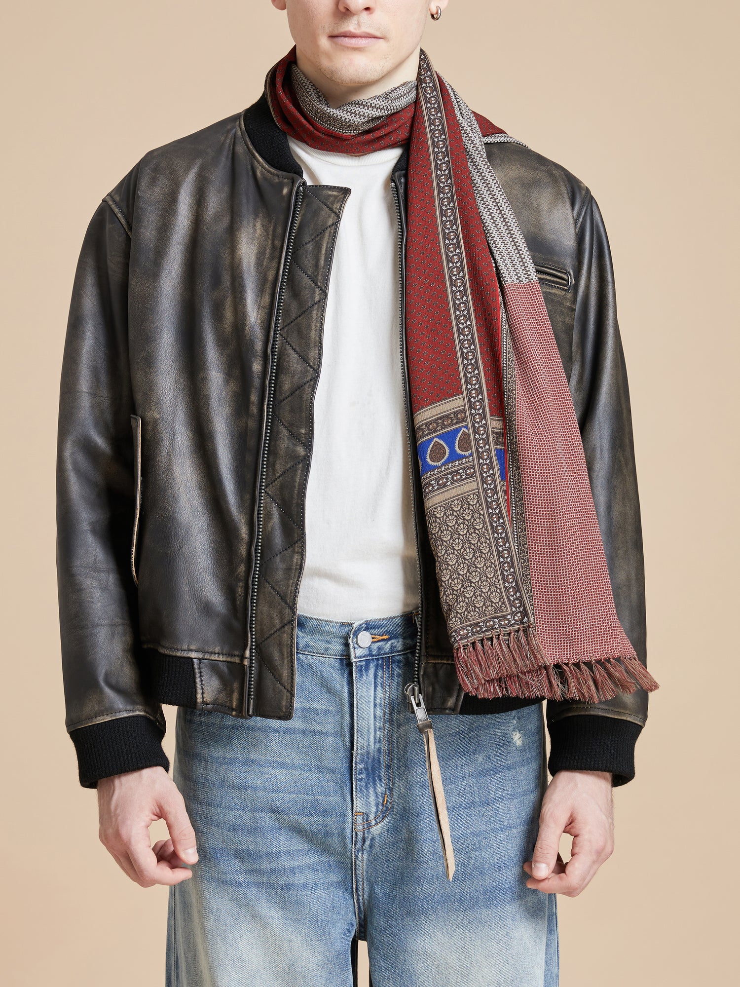 A man in jeans and a leather jacket wearing a Found Paisley Medley Scarf.