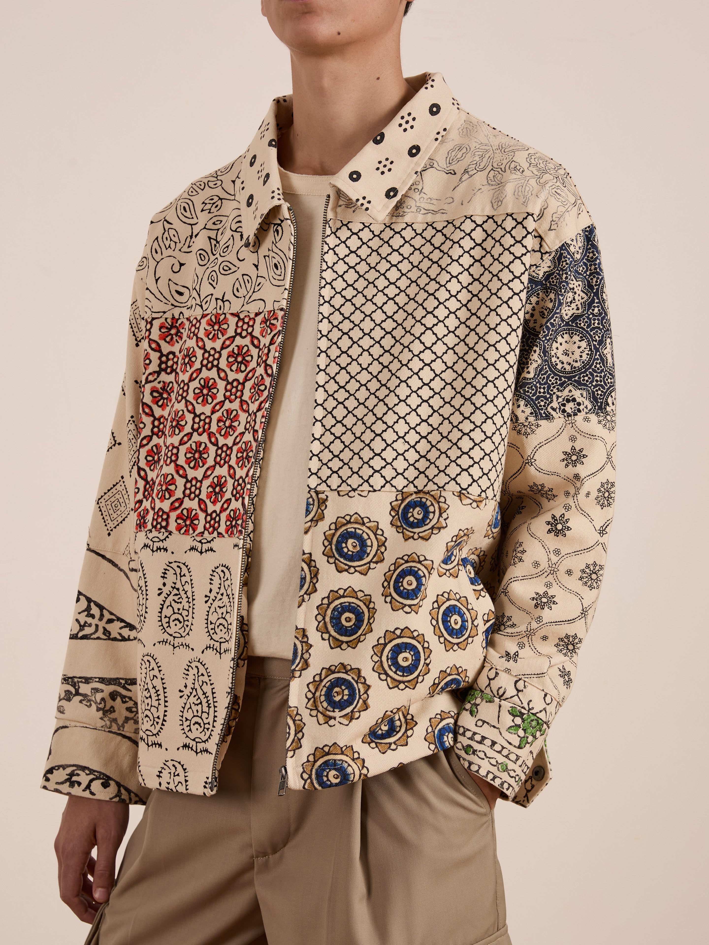 A person wears the FOUND Paisley Mosaic Work Jacket over a beige shirt and tan pants.