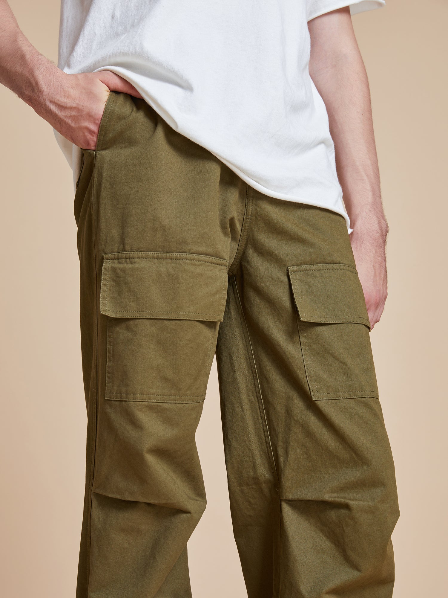 A man wearing Found Parachute Cargo Twill Pants and a white t - shirt.