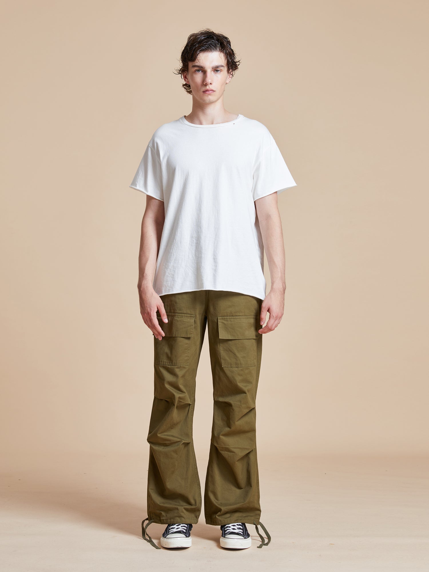 A man wearing a white t-shirt and Found Parachute Cargo Twill Pants.