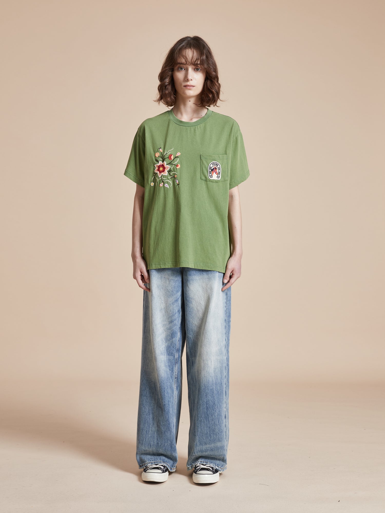 A woman wearing a Found Pine Needle Farm Tee and jeans.