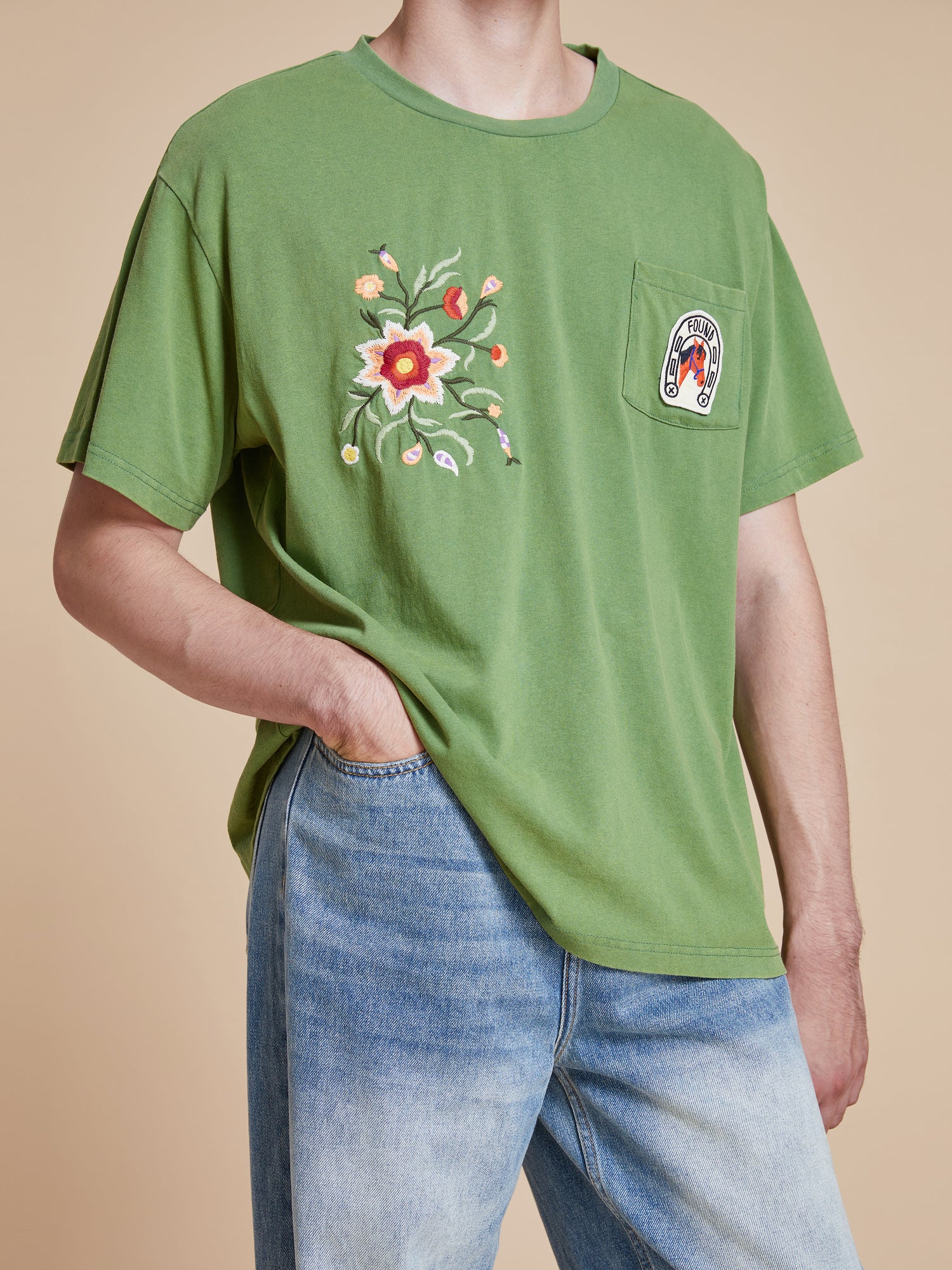 A man wearing a Pine Needle Farm Tee from Found and jeans.