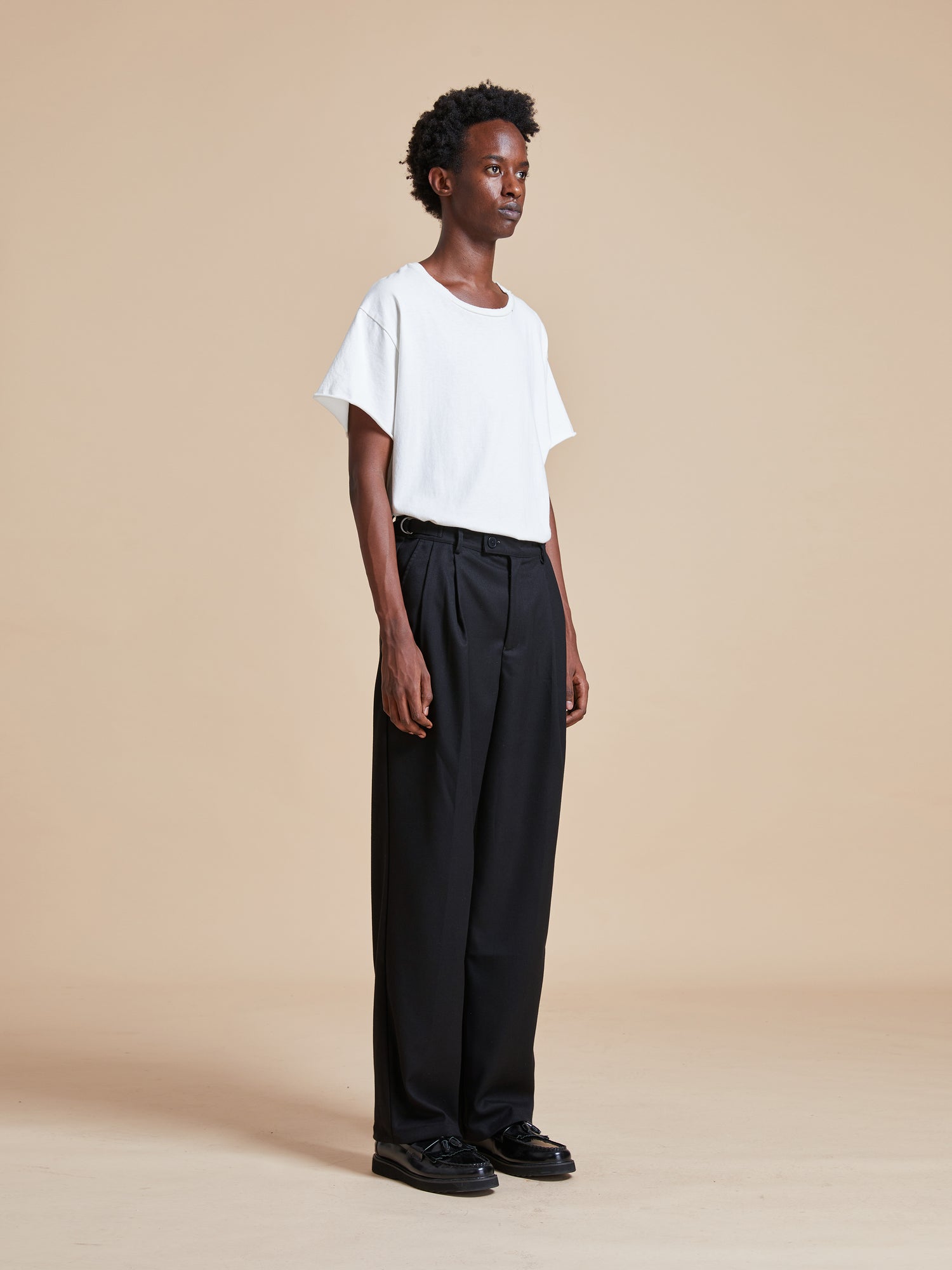 The model is wearing a white t - shirt and Found pleated trousers.