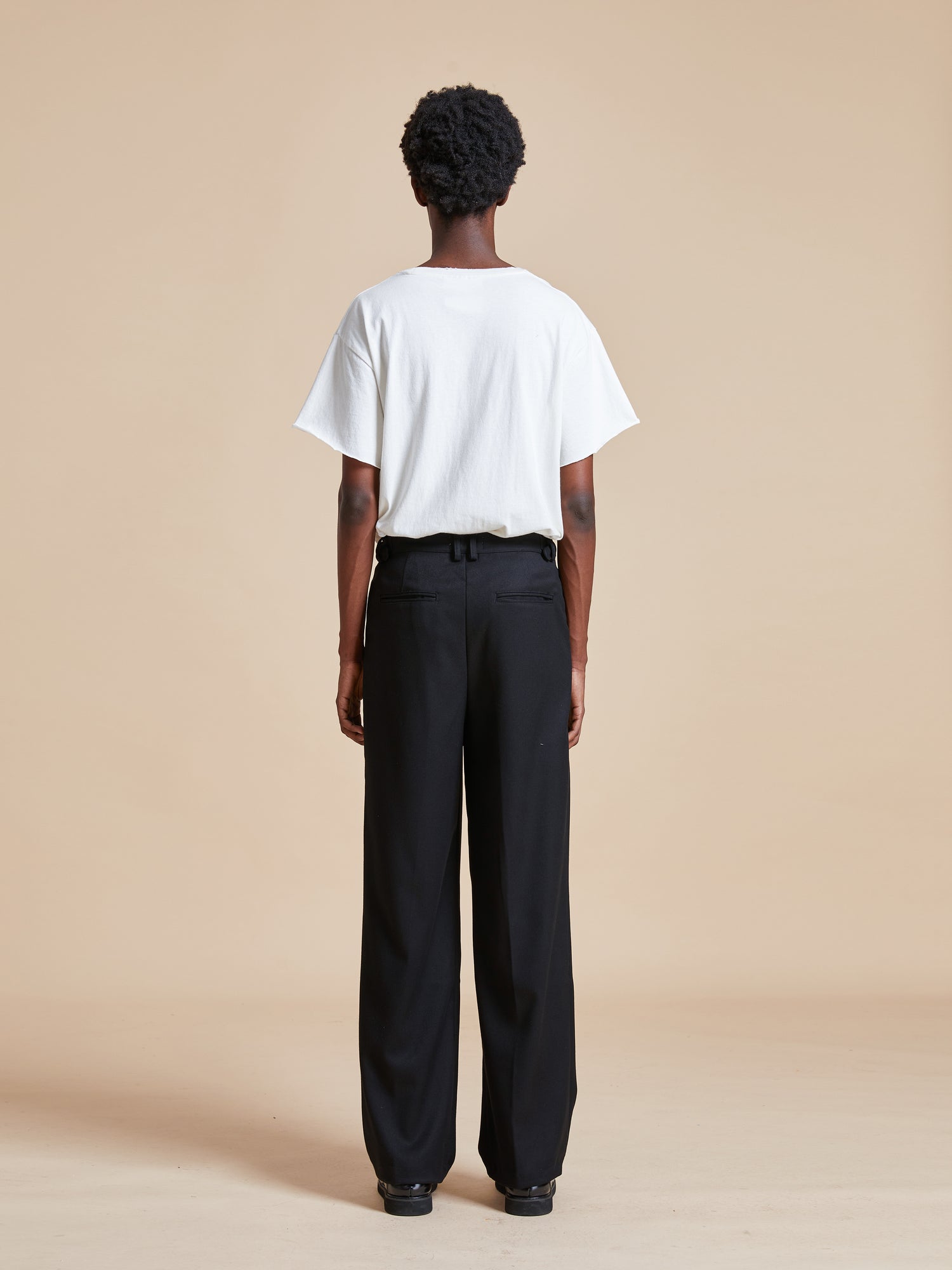 The back view of a woman wearing Found black wide leg Pleated Trousers.