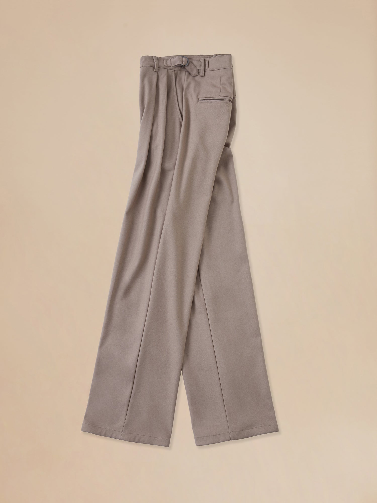 A pair of Found Pleated Trousers in beige on a beige background.