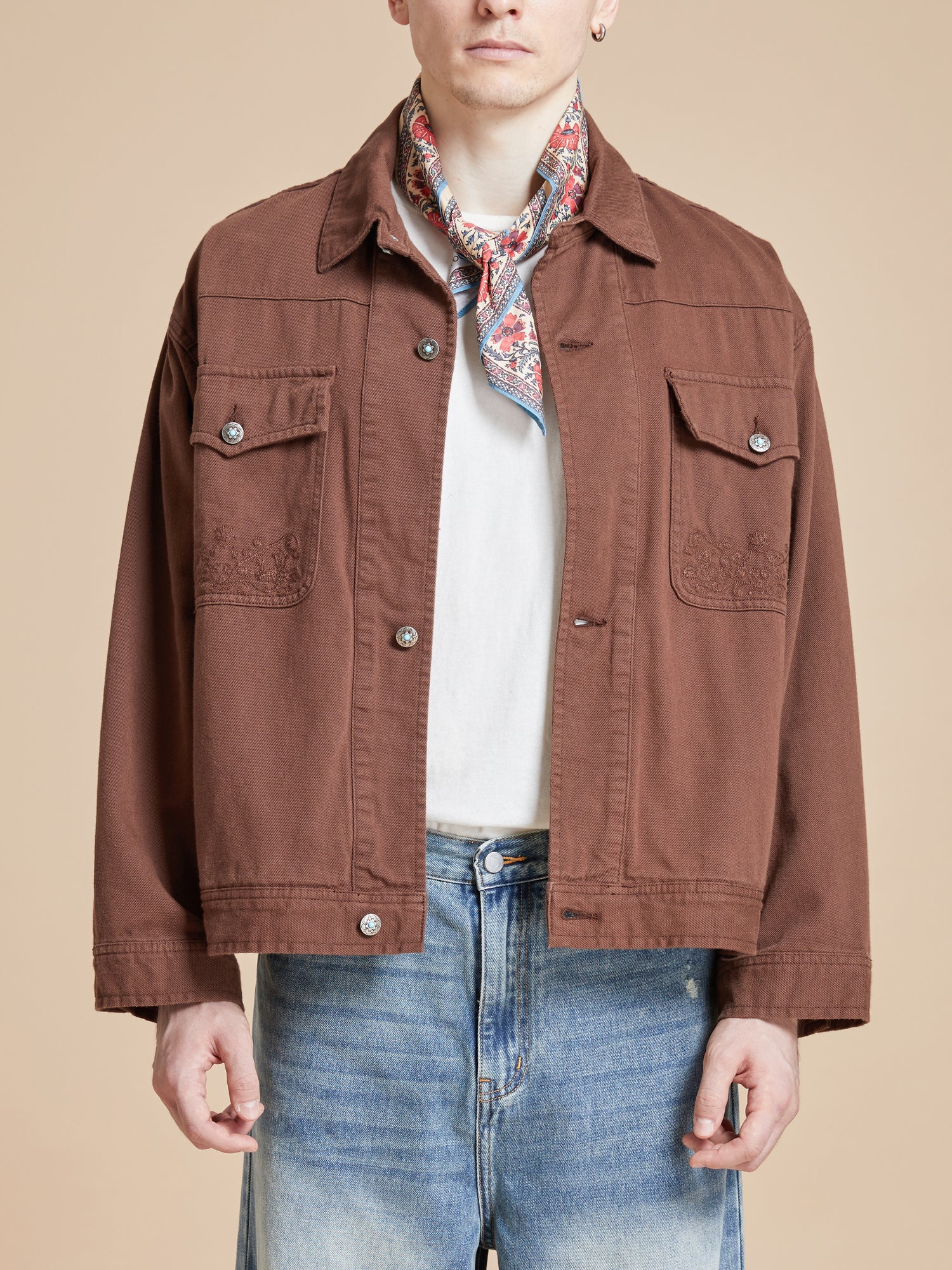 The model is wearing a brown jacket and jeans from Found.