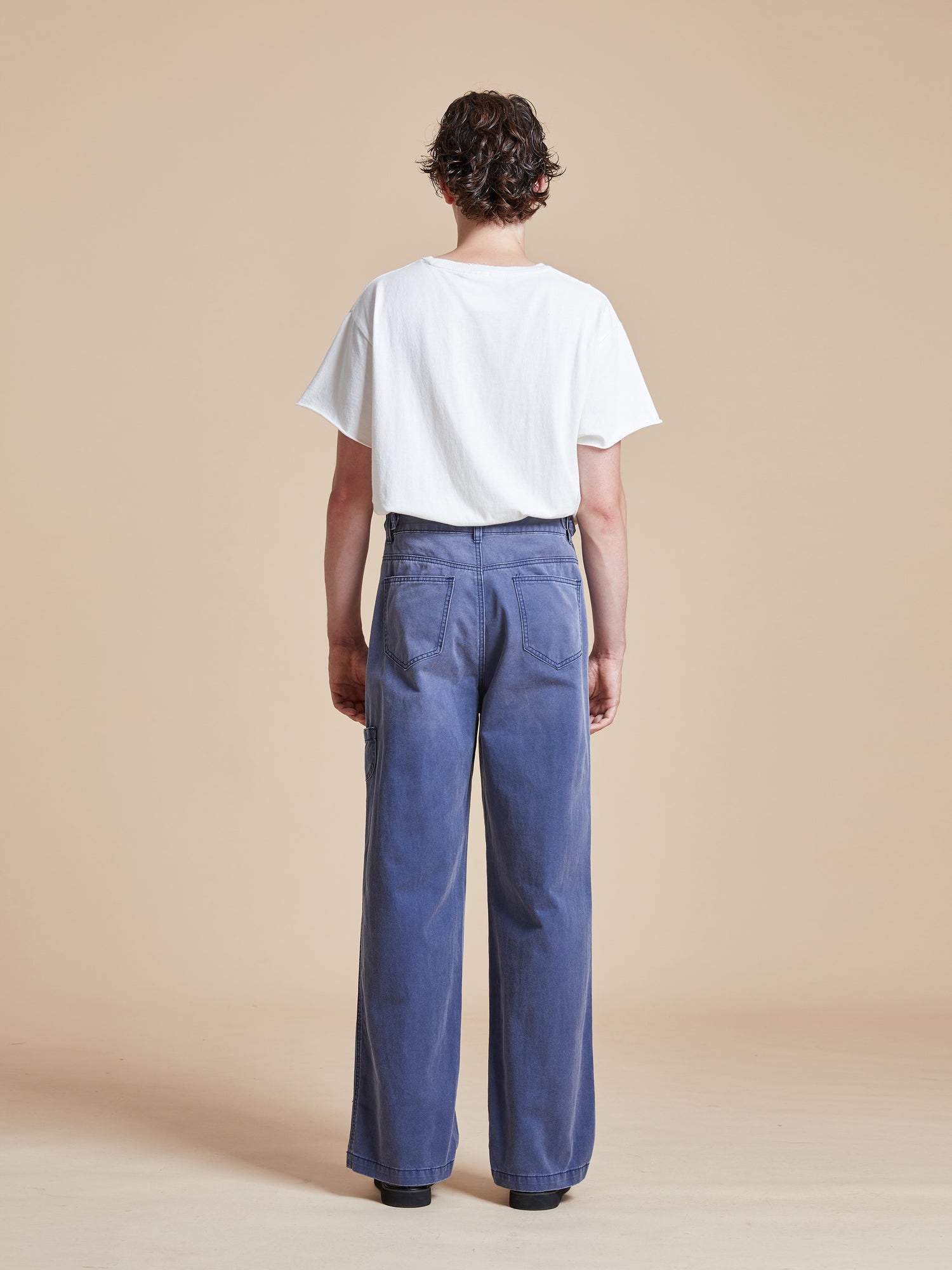 The back view of a man wearing Found River Painters Chore Pants.