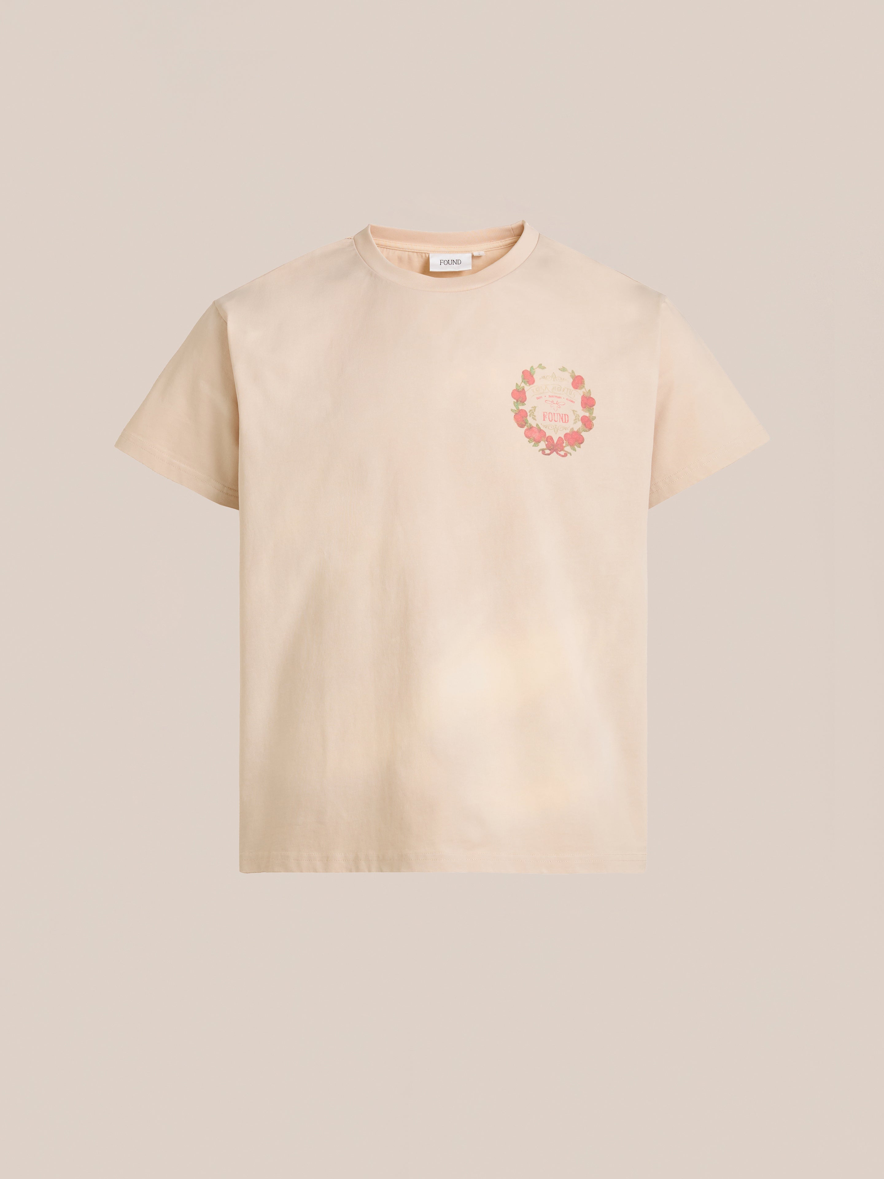 The FOUND Rose Garden Tee is a beige, short-sleeve T-shirt with a vintage-inspired floral wreath graphic on the front left side.