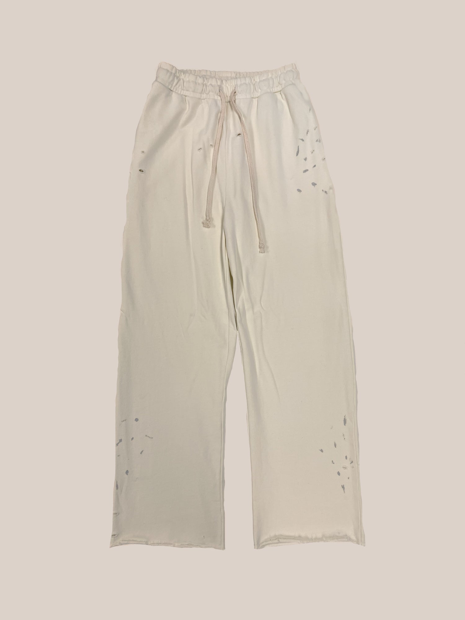 A pair of Sample 35 cream-colored, drawstring lounge pants with distressing and holes by Profound.