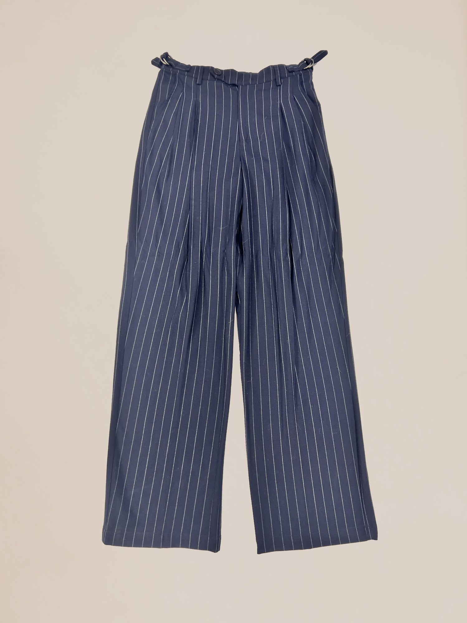 Pre-production Profound Sample 38 navy pinstripe trousers with a gathered waist on a beige background.
