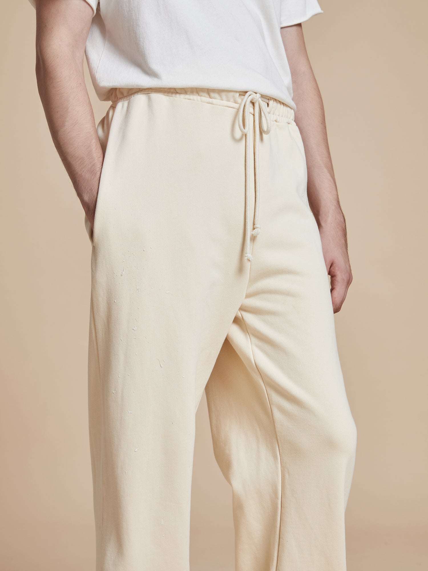 A man donning a white t-shirt and beige Sandshell Lounge Pants, a perfect wardrobe staple for that worn-in look by Found.