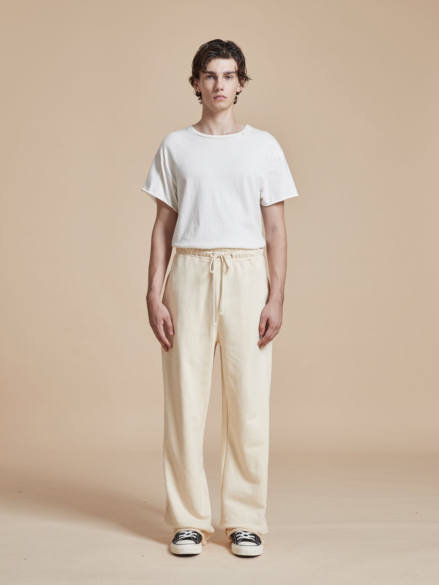 The model is wearing a white t-shirt and Found Sandshell Lounge Pants - a wardrobe staple.