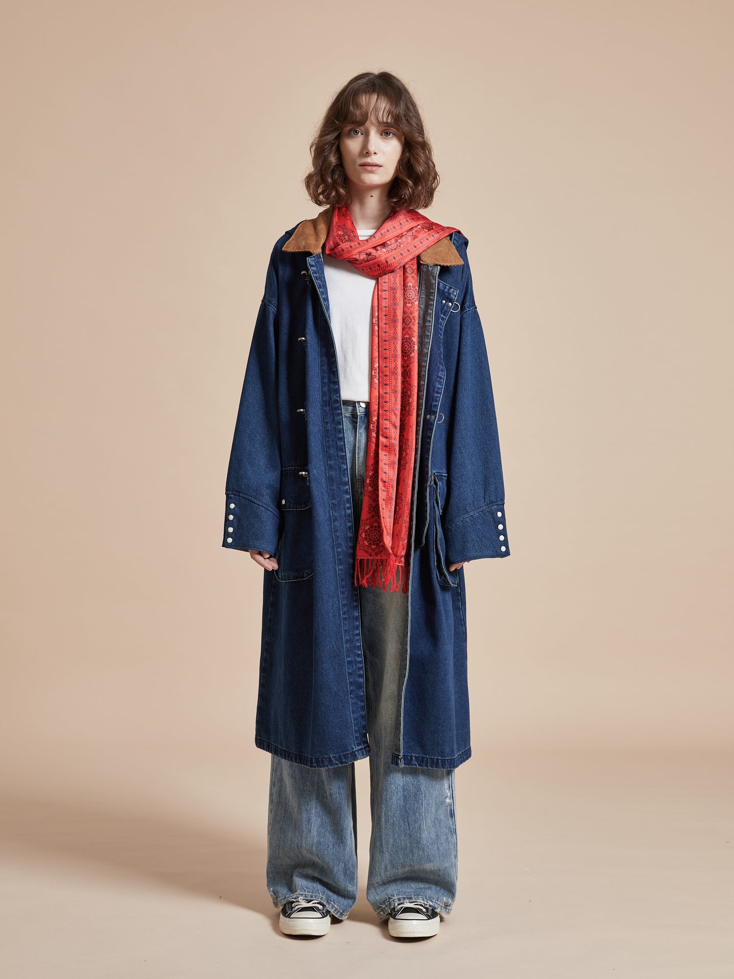 A woman wearing a Sargasso Denim Buckle Coat from Found and a red scarf.