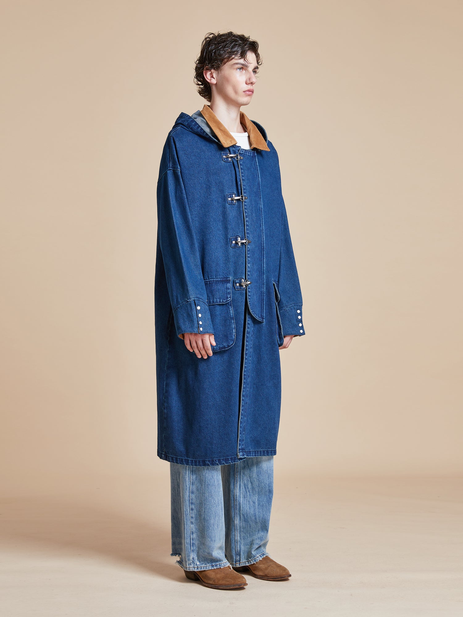 A model wearing a Sargasso Denim Buckle Coat and jeans by Found.