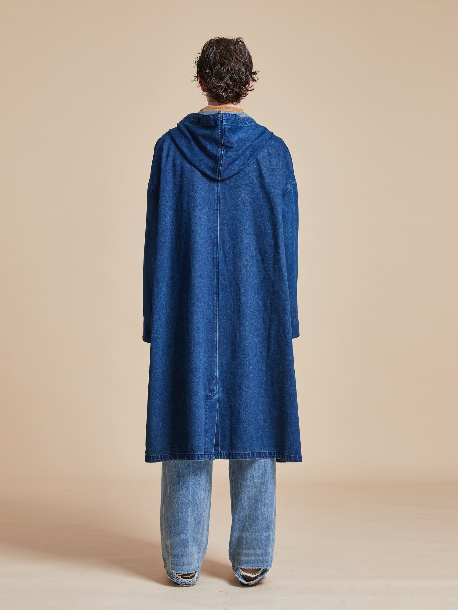The back view of a man wearing a Sargasso Denim Buckle Coat by Found.