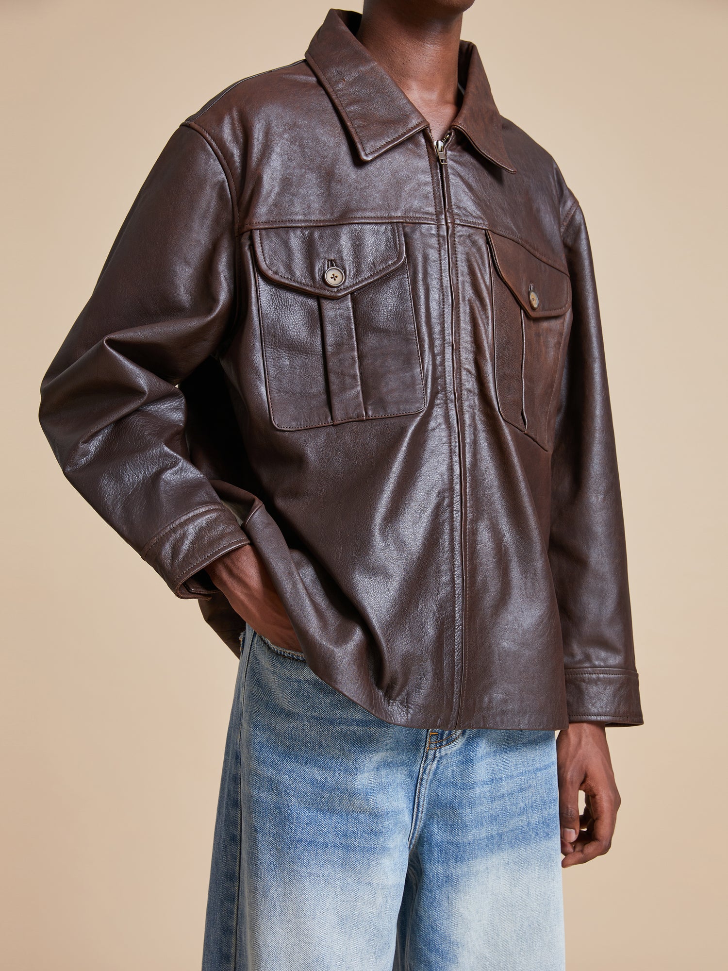 A man wearing a Found Sepia Leather Overshirt and jeans.