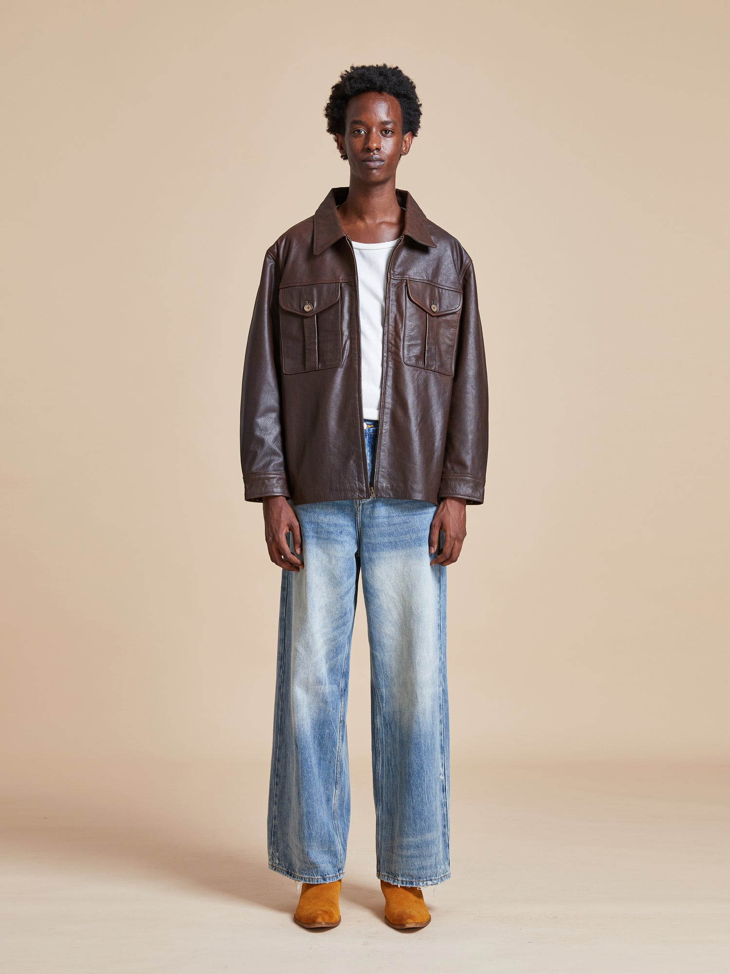 The model is wearing a Sepia Leather Overshirt by Found and jeans.