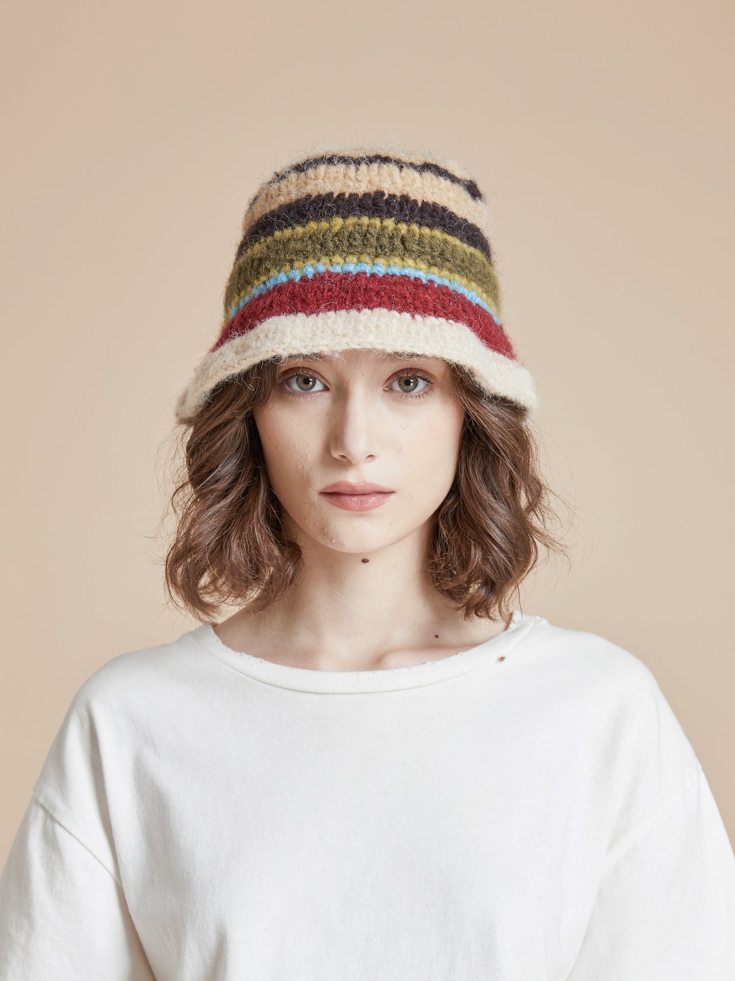 A woman wearing a Found stripe knit beanie with a multi-color stripe pattern.