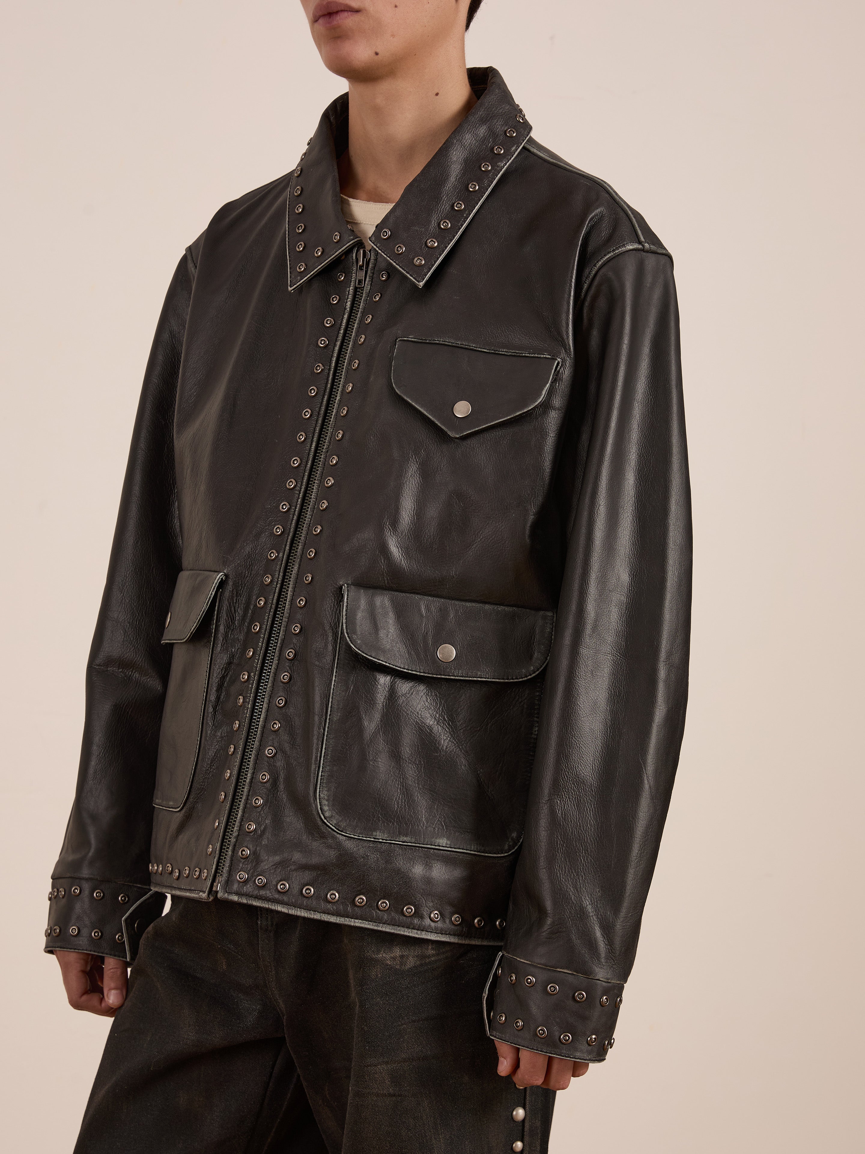 A person wearing a Found Studded Leather Pocket Jacket, a vintage black piece with metal studs, front pockets, and a zipper.