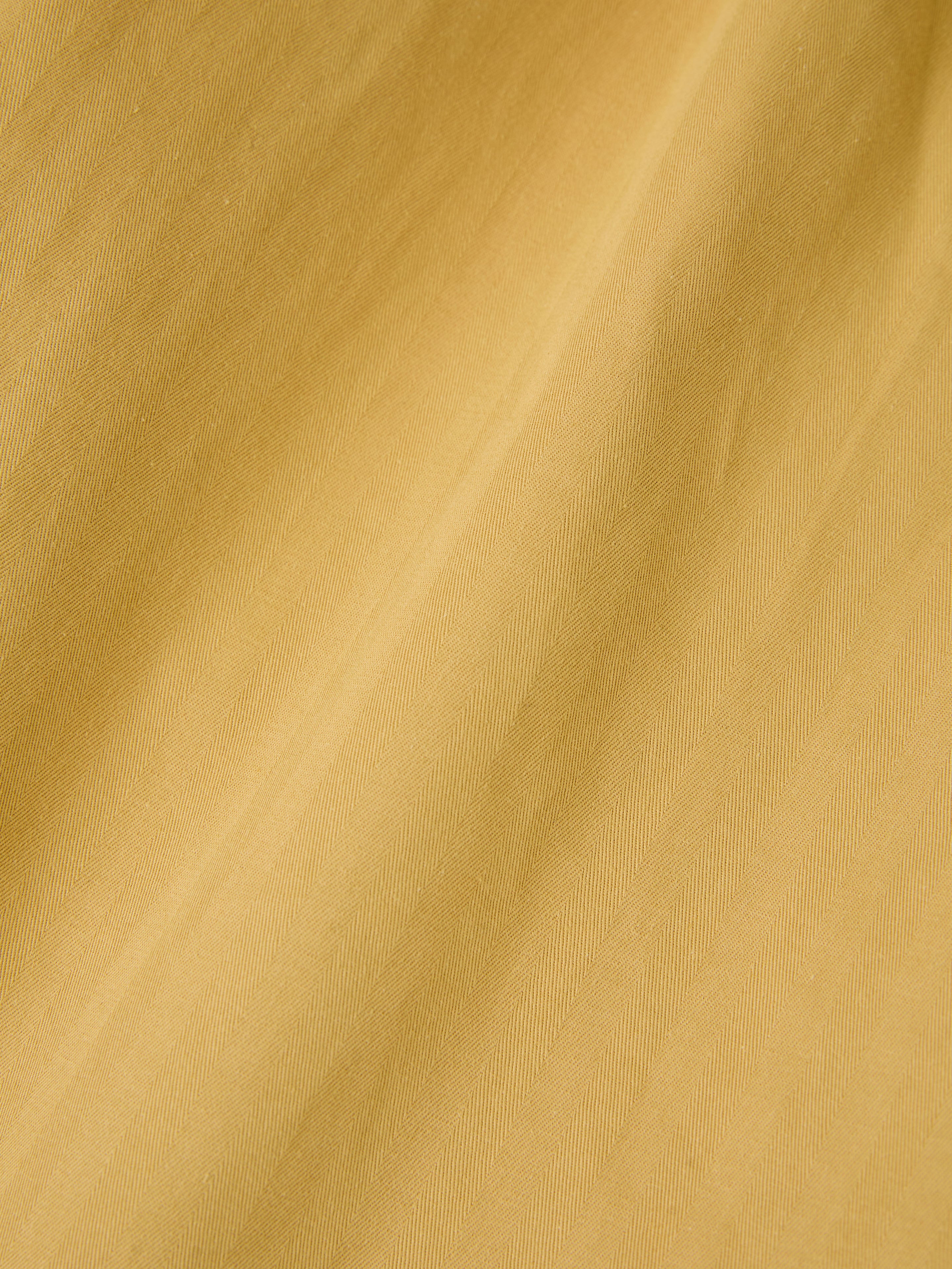 Close-up of a yellow fabric with a subtle diagonal texture pattern, reminiscent of the relaxed fit found in FOUND's Sunlight Twill Cargo Pants.