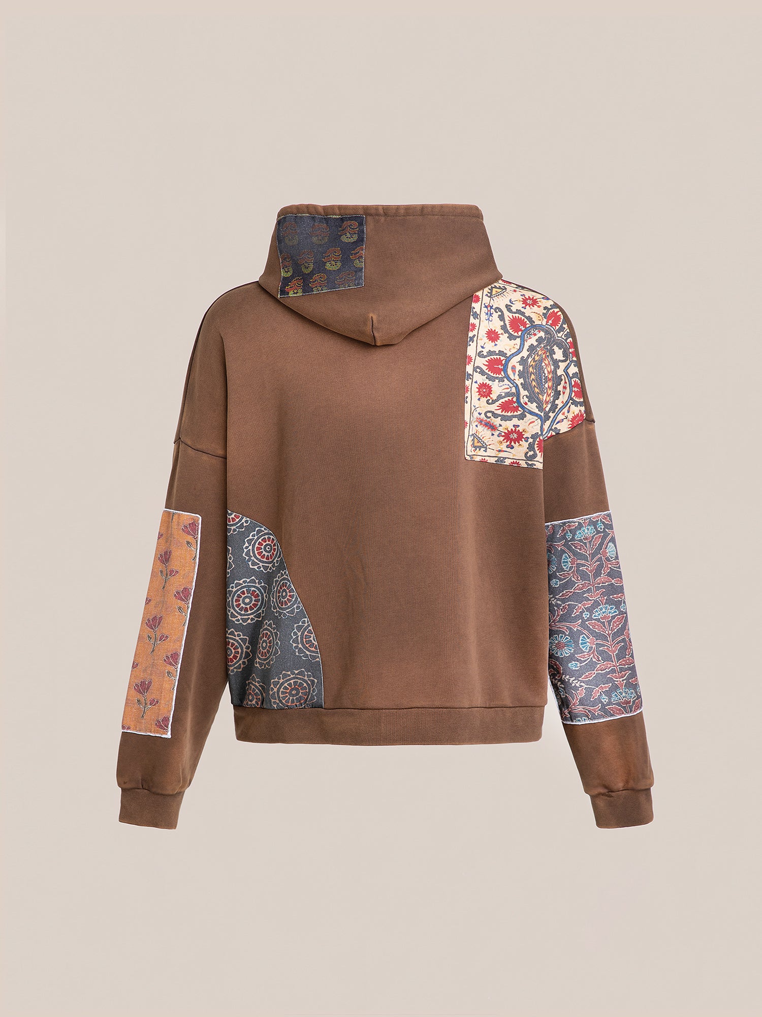 The Tapestry Patchwork Zip Up Hoodie by FOUND features an oversized fit with a patchwork design inspired by South Asian tapestry, showcasing multicolored floral and geometric patterns on the back and sleeves.