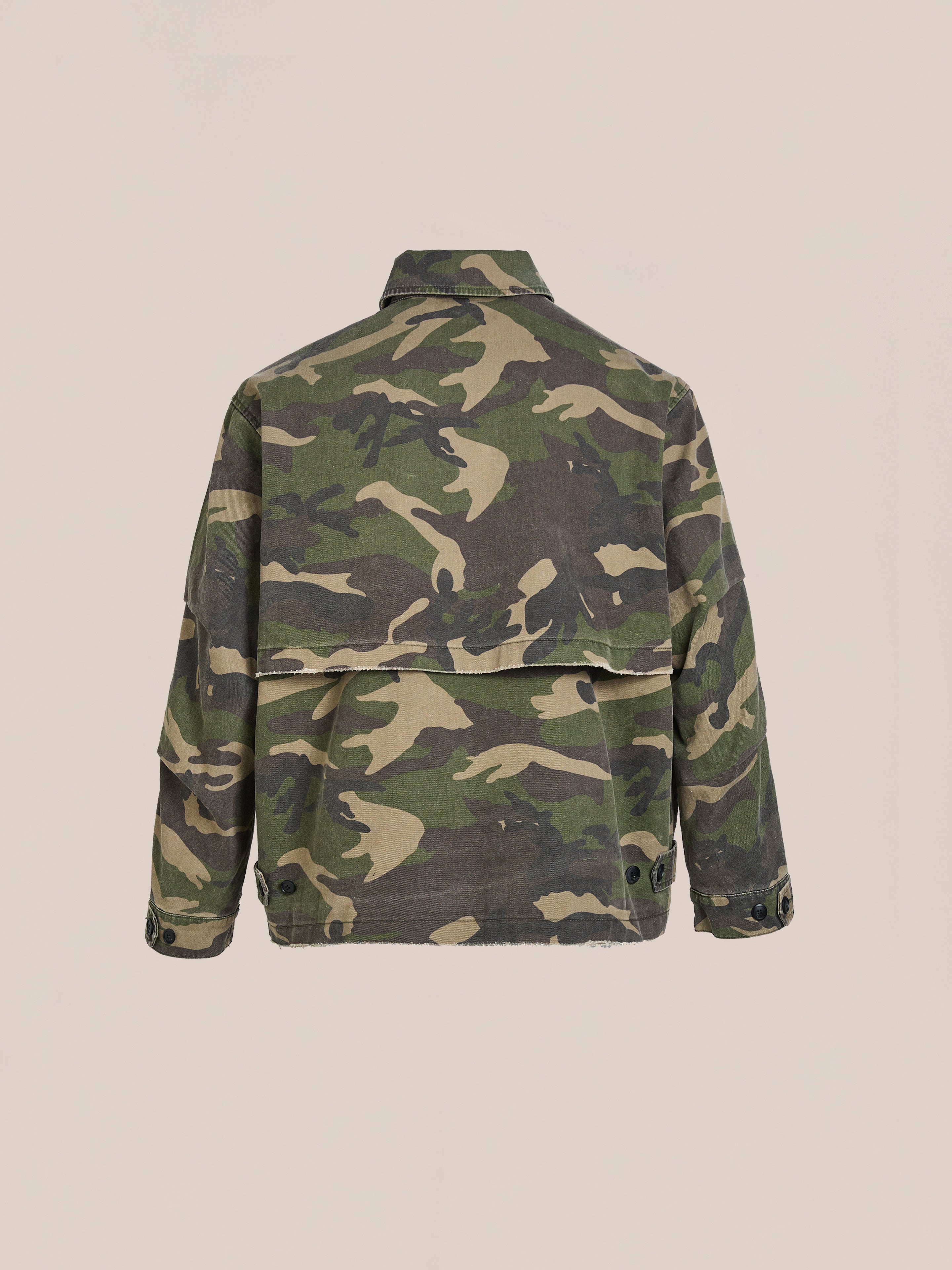 The FOUND Camouflage Twill Utility Cargo Jacket, with long sleeves and a back flap for a vintage look, is displayed on a neutral beige background.