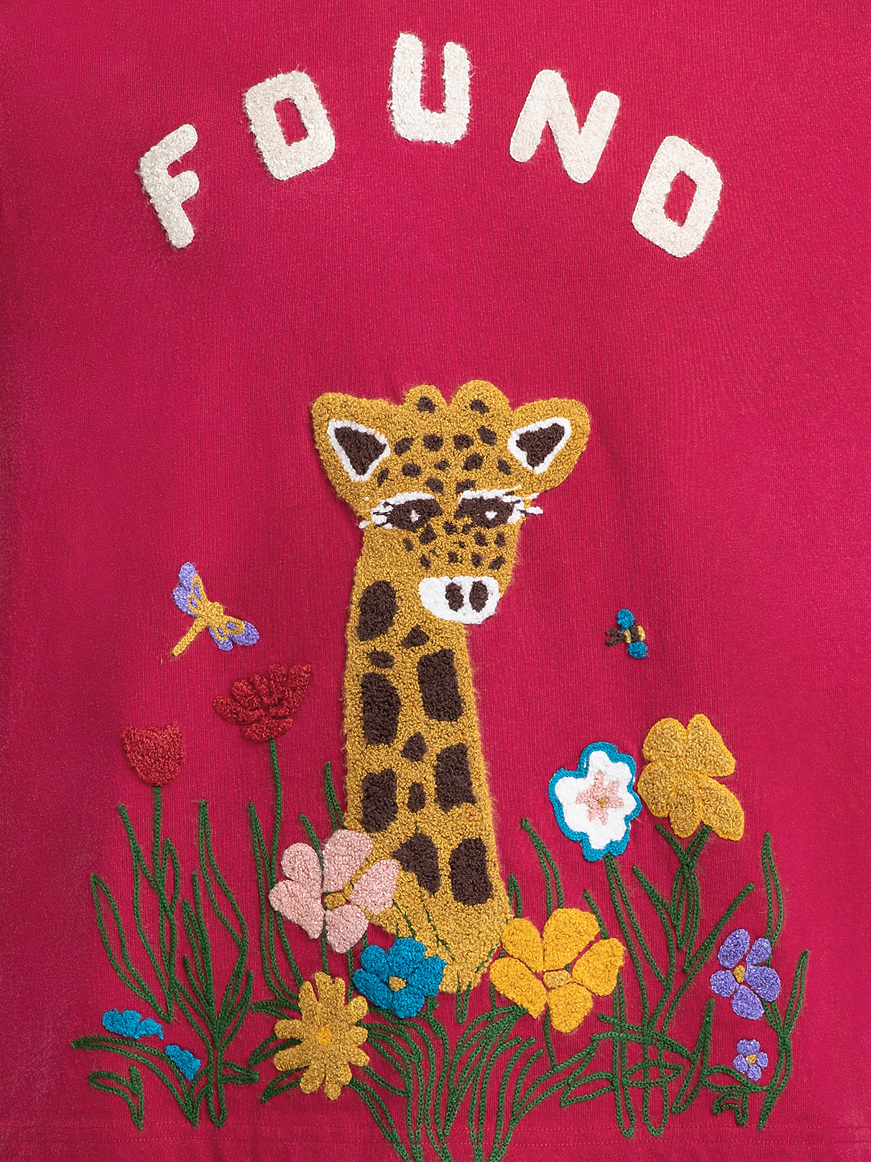 The FOUND Embroidered Wildlife Tee features a giraffe amid colorful flowers and insects on red fabric, with "FOUND" chenille embroidered above, celebrating nature-inspired artistry.