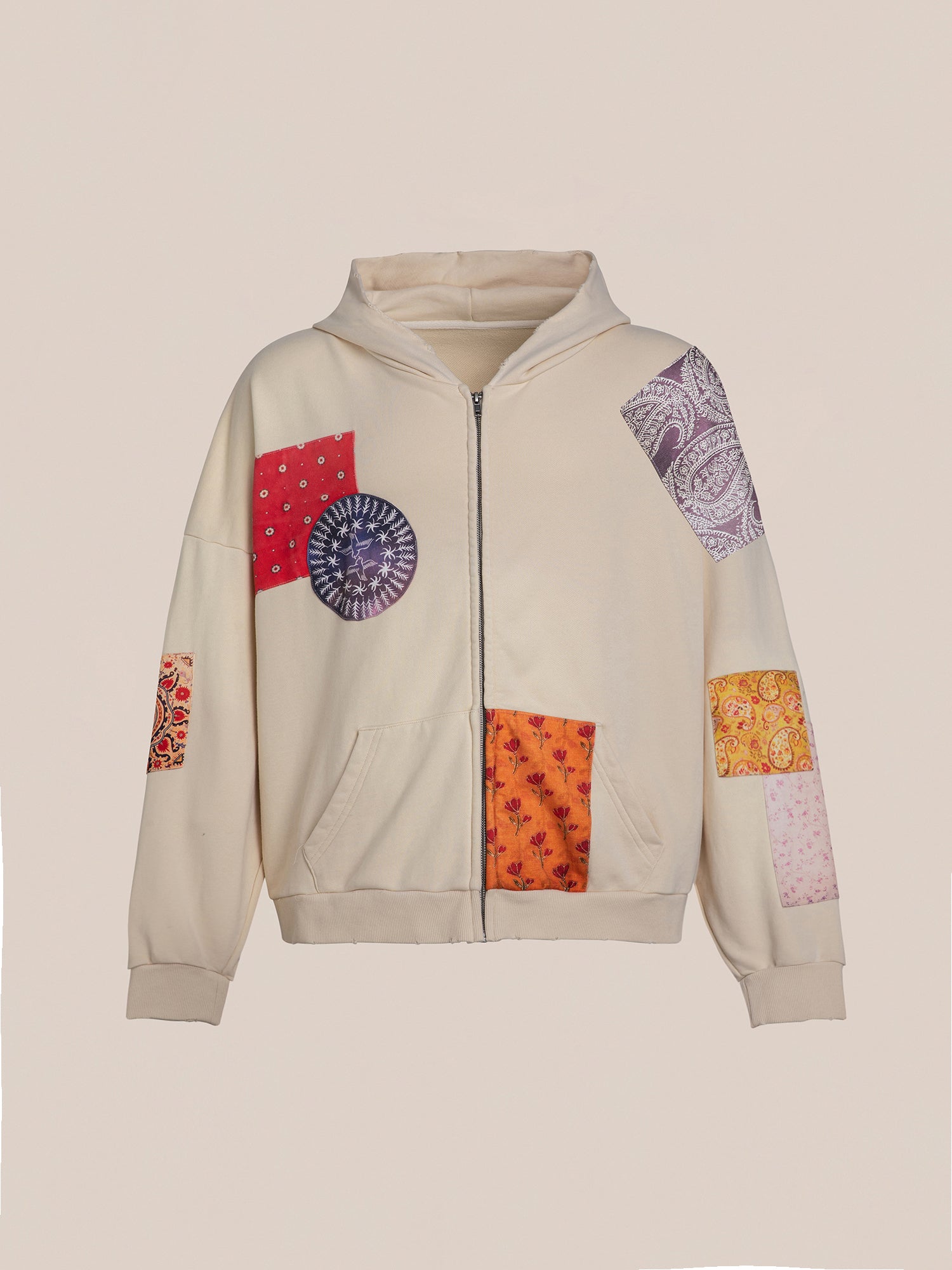 Introducing the FOUND Patchwork Hoodie, a cream zip-up featuring vibrant South Asian patterns in red, purple, and orange against a plain beige background. This oversized hoodie combines comfort and style effortlessly.