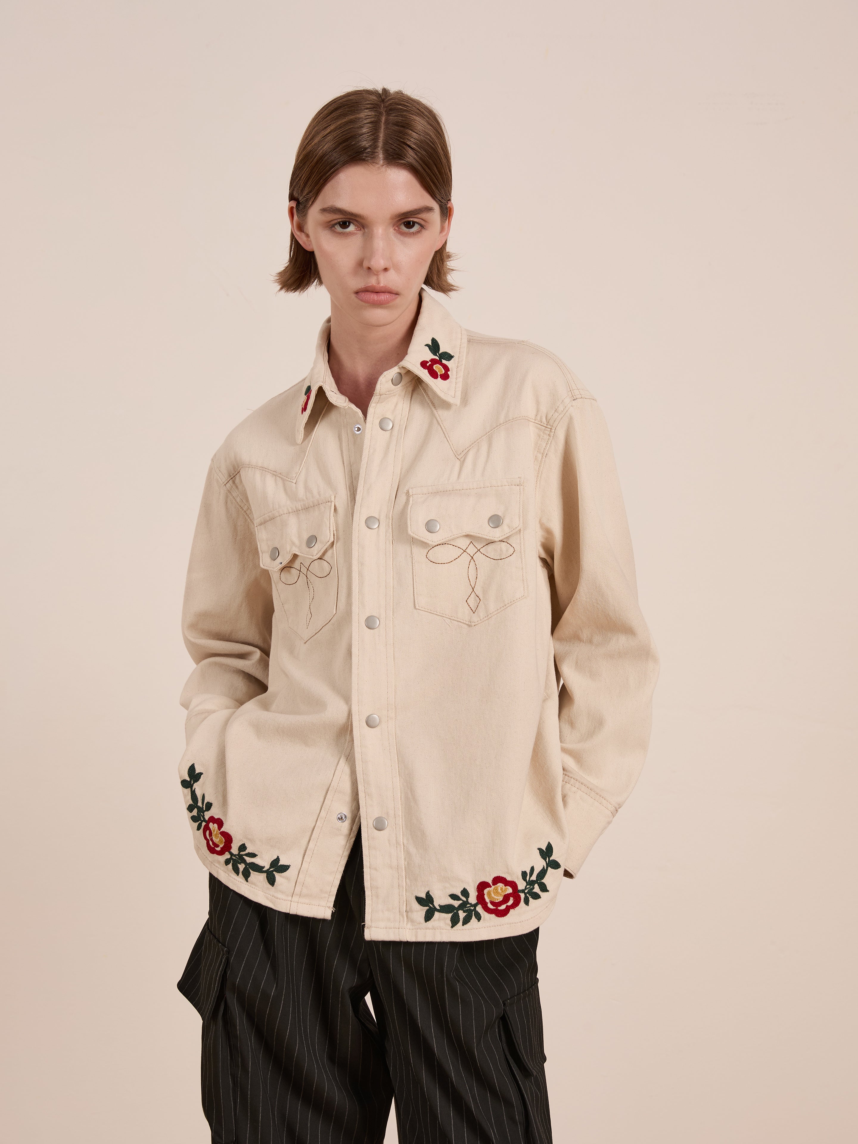 Wearing the Western Floral Denim Shirt by FOUND, with its floral chainstitch embroidery on the collar and cuffs, paired with black pinstriped pants, creates a stylish yet understated look.