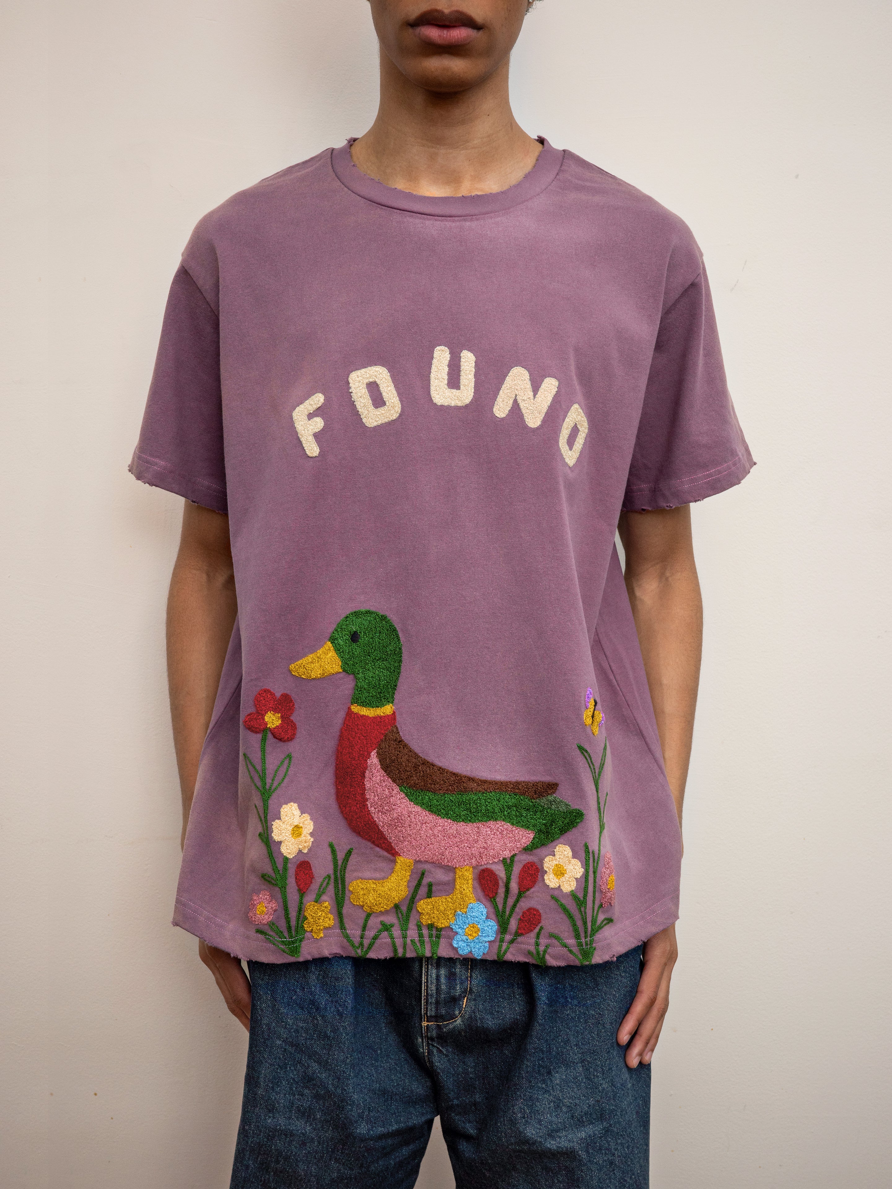 A person wearing the FOUND Embroidered Wildlife Tee featuring a cute chenille duck with flowers on the front, paired with blue jeans.