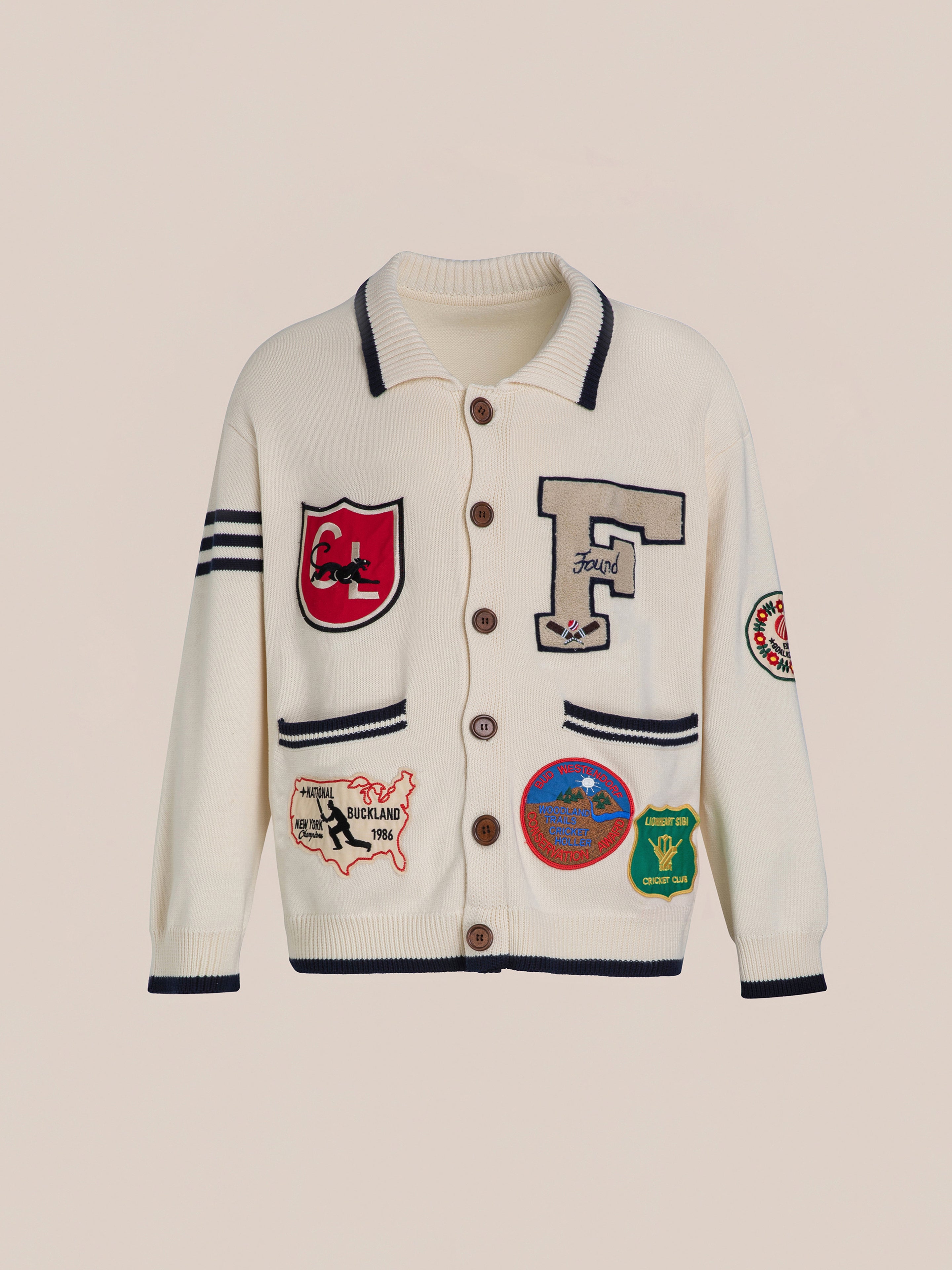 The York Varsity Patch Collared Cardigan by Found is a vintage-style piece crafted from a soft cotton blend. It features large buttons, diverse patches like letters and animals, circular designs, and stripes on the sleeves.