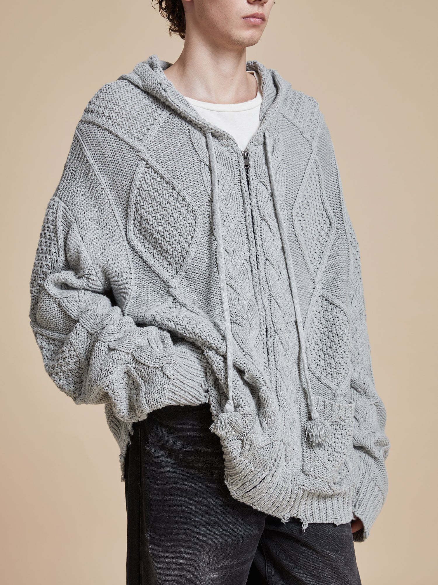 The model is wearing a warm Found Zip Up Distressed Cable Knit Hoodie sweater.