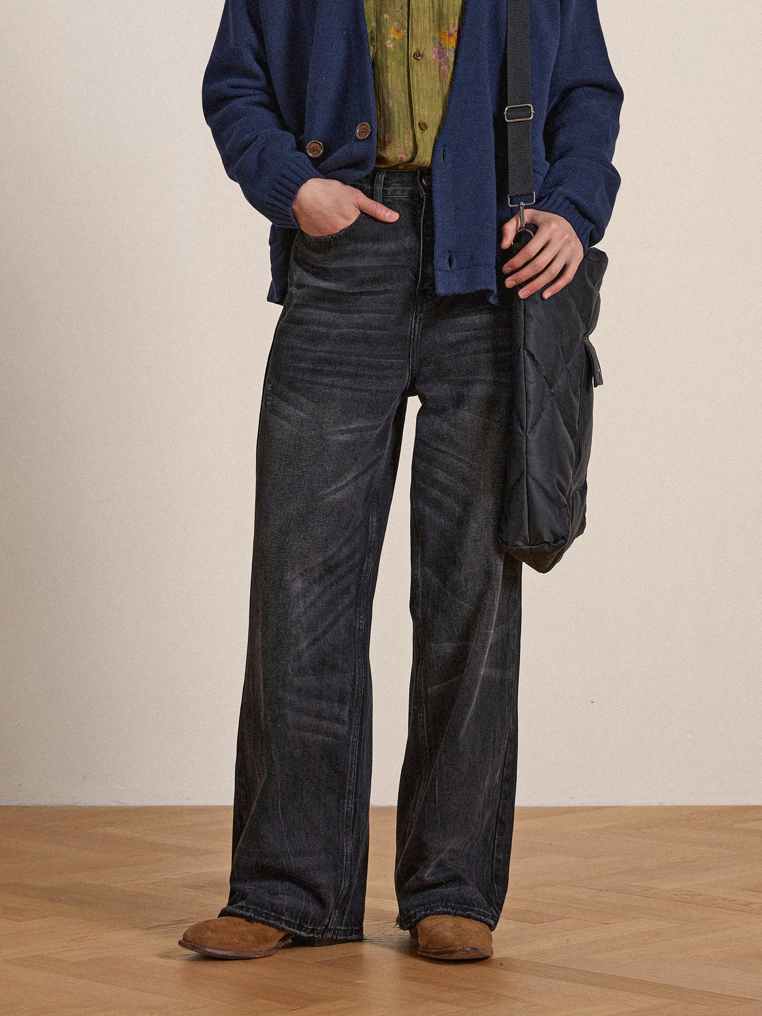 Man in a blue jacket, patterned shirt, and wide-leg black denim jeans standing with a Found Lacy Baggy Jeans, focusing on his mid-section and legs.