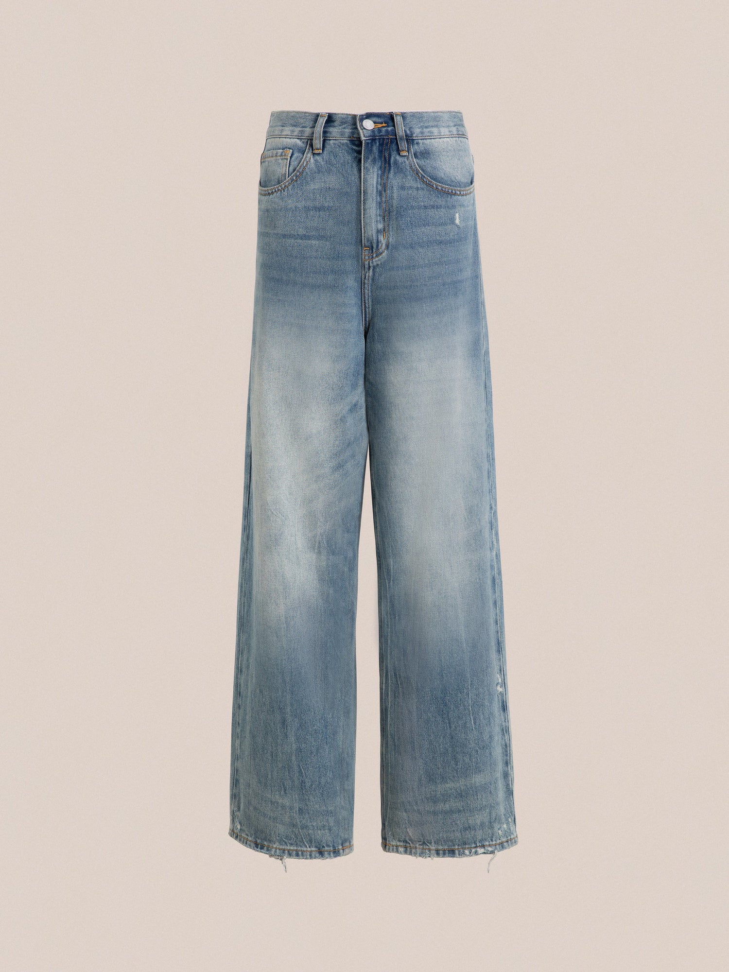 A pair of Found Lacy Baggy Jeans with a vintage blue wash and frayed hems, displayed against a light pink background.