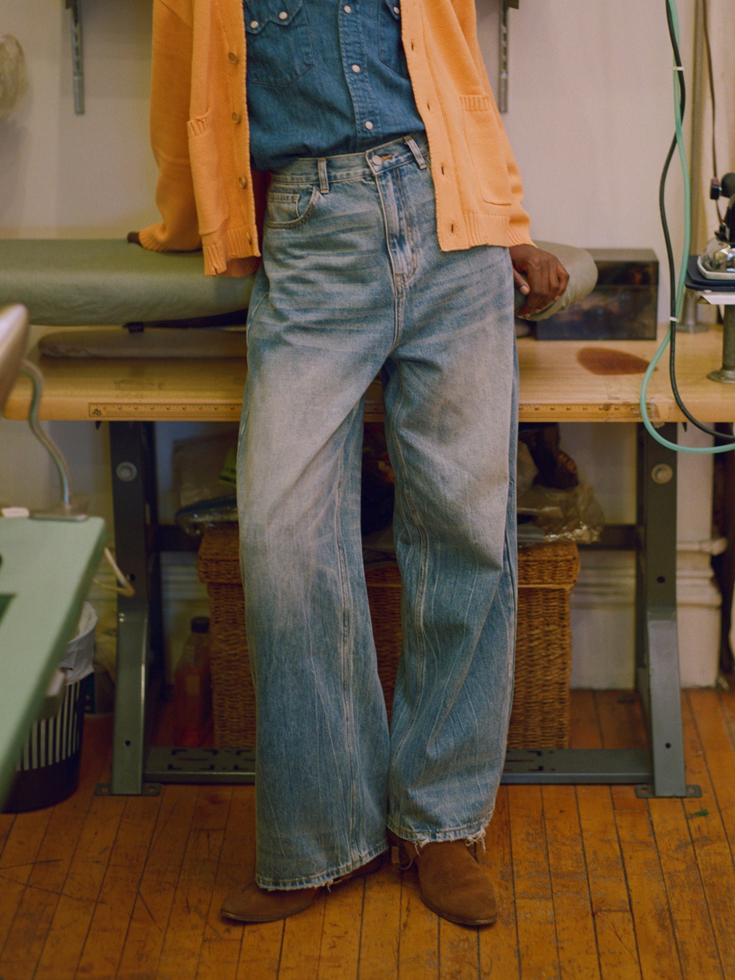 A woman is standing in a workshop wearing Found's Lacy Baggy Jeans Blue with distressed hems.