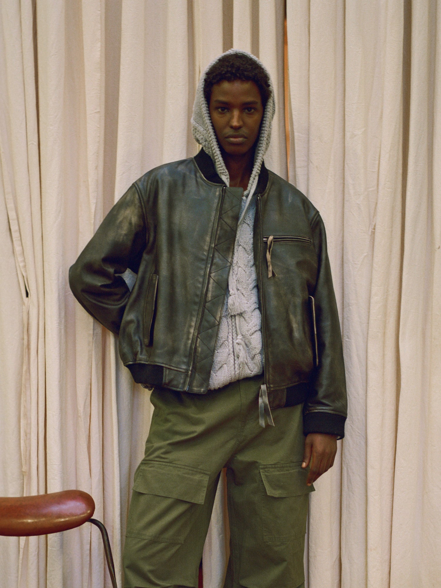 A man wearing a Found Distressed Pavement Leather Bomber Jacket and green pants.