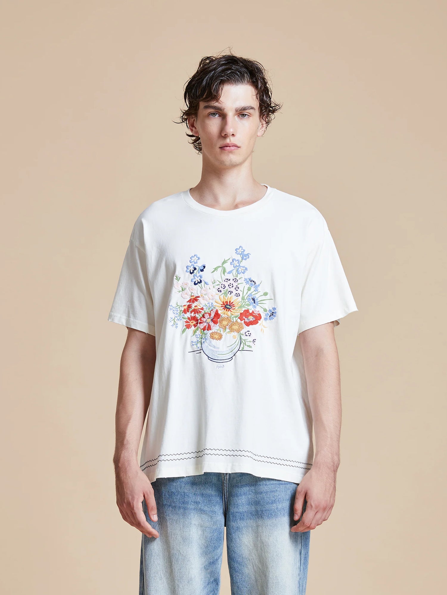 A man wearing a white Bouquet Flowers Tee from Found, showcasing traditional Phulkari embroidery from Punjab.