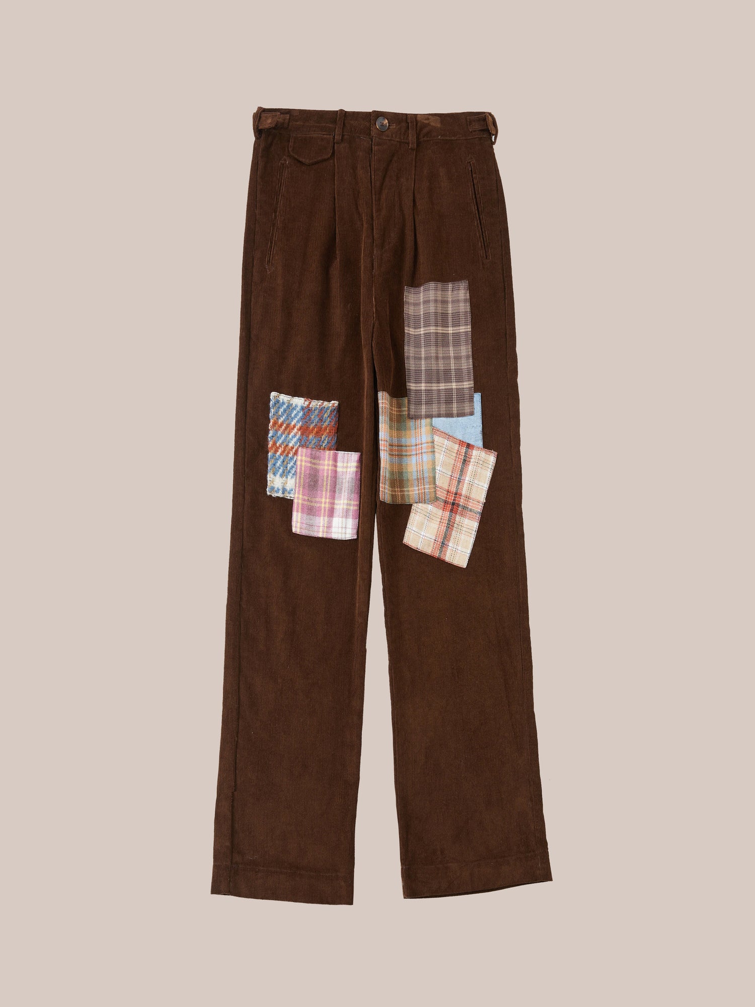 Brown corduroy pants with Found Multi-Plaid Patch details on the pockets against a light tan background.