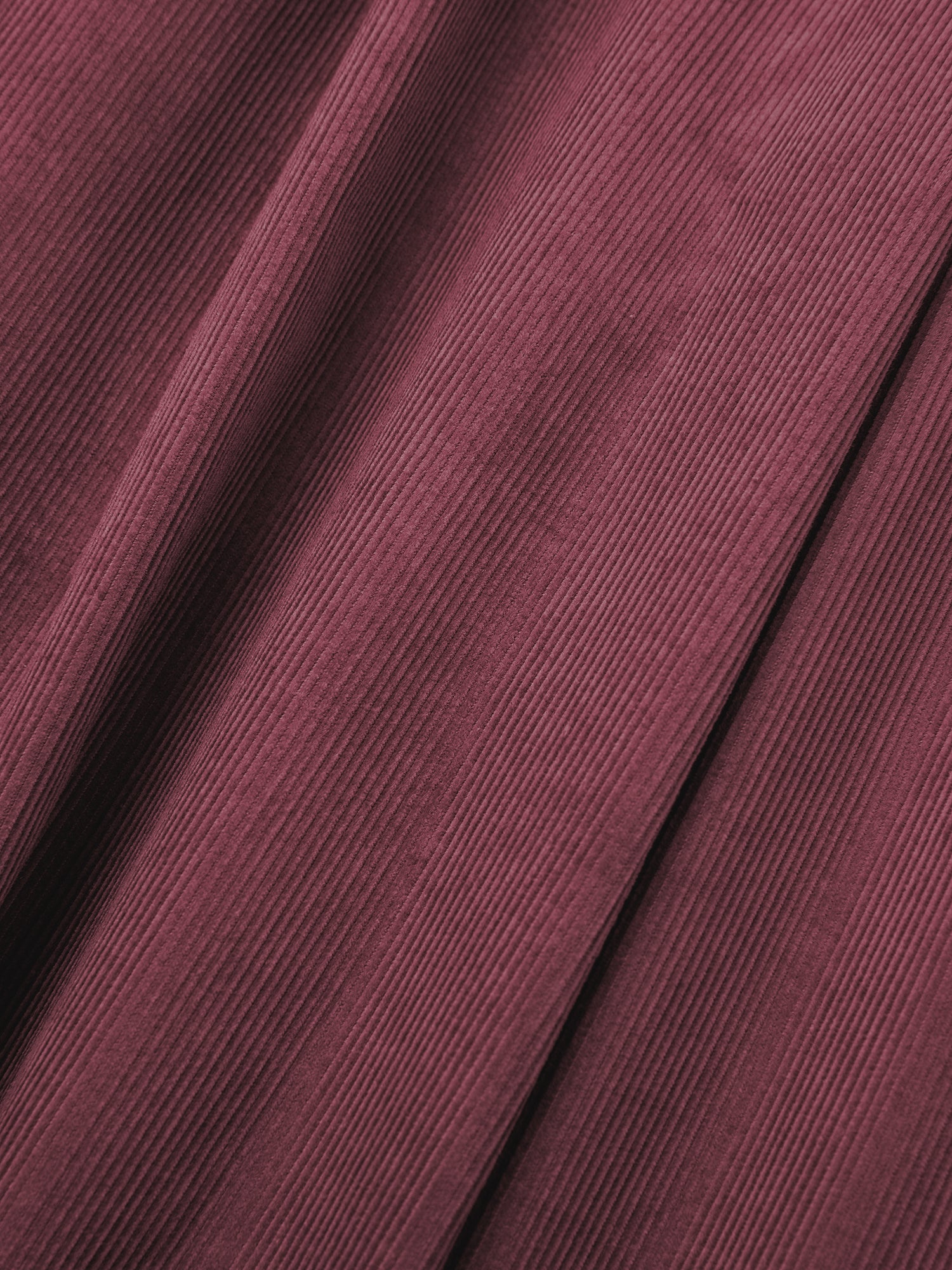 Close-up of the Corduroy Pleated Trouser by FOUND, featuring maroon corduroy fabric with visible vertical ridges and folds, reminiscent of a design with double pleats and a high-rise waist.