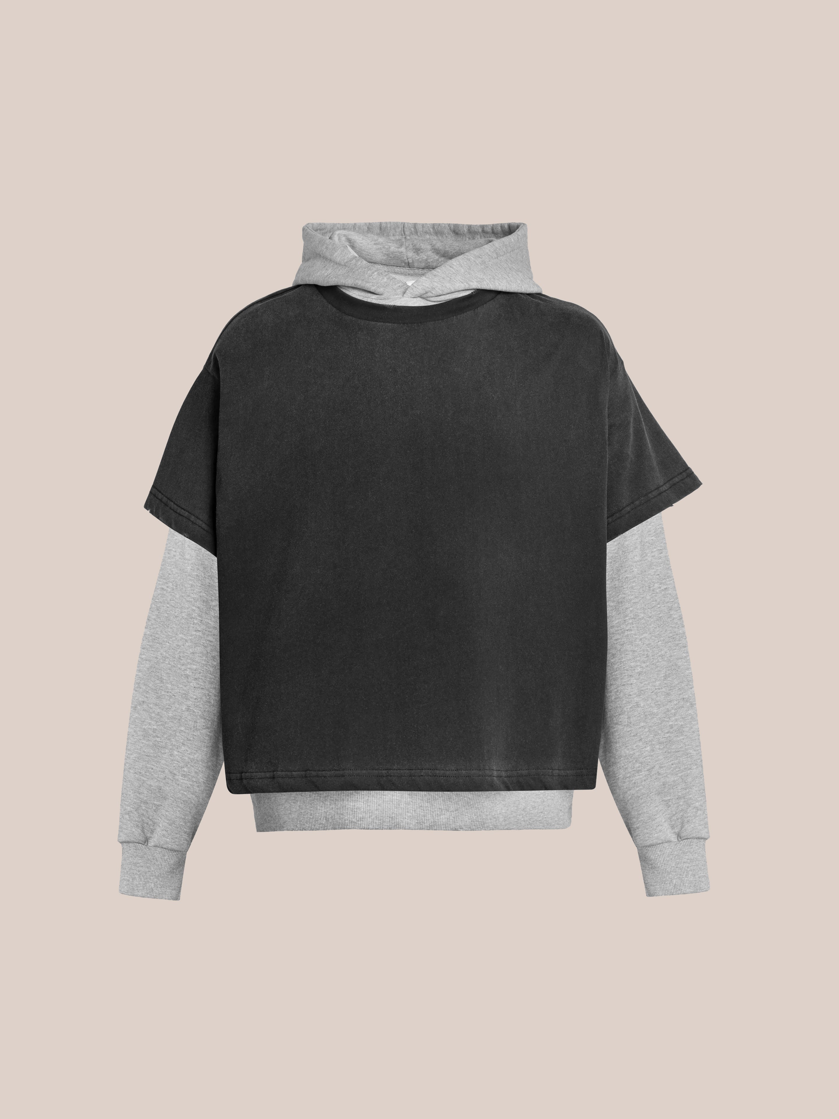 The Found Double Layer Hoodie pairs a black short-sleeve layer over a light gray long-sleeve hoodie, made from French terry cotton for a vintage look, and is shown against a plain beige background.